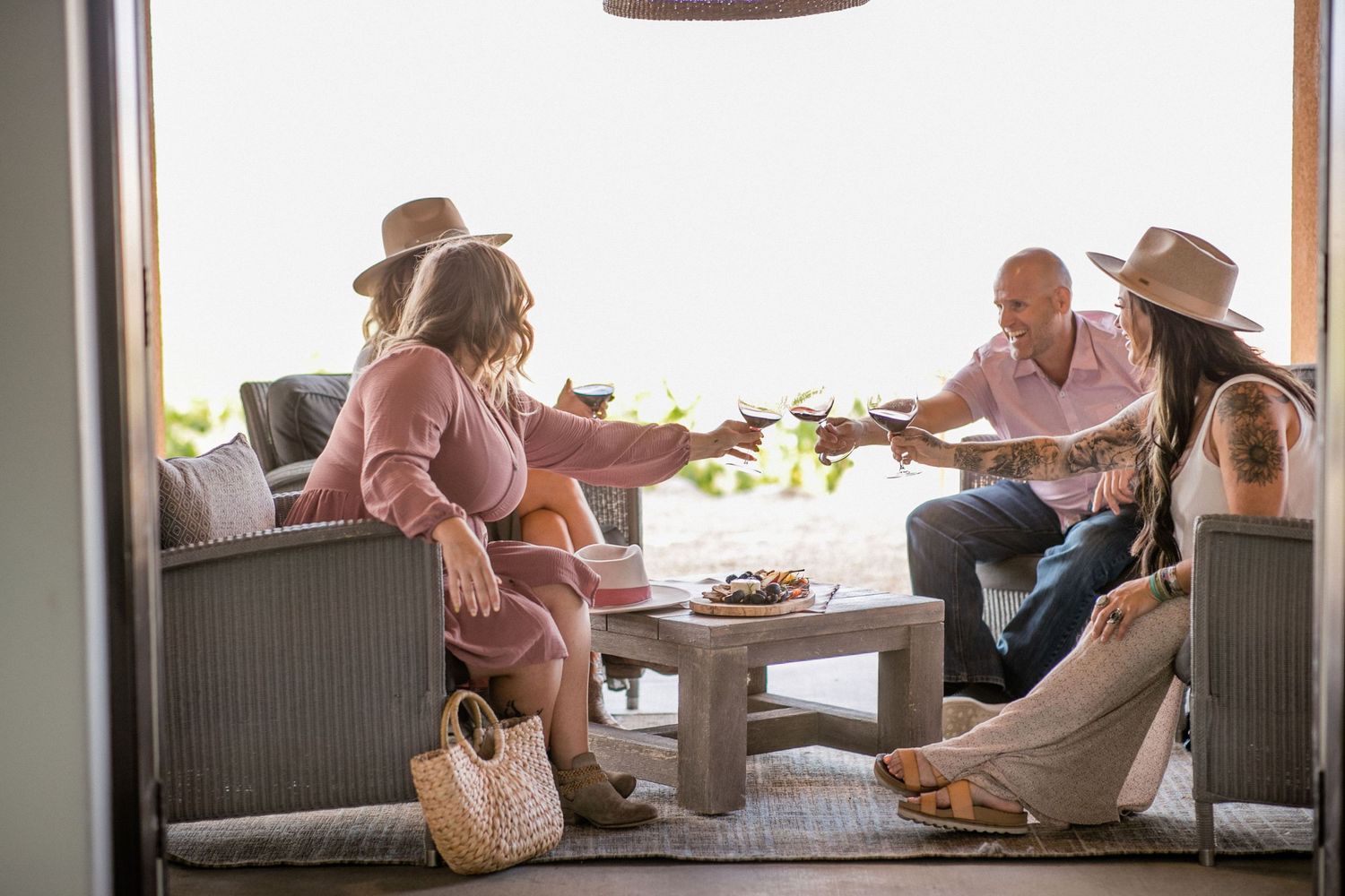 Friends enjoying drinks and conversation while relaxing on a covered patio during golden hour.