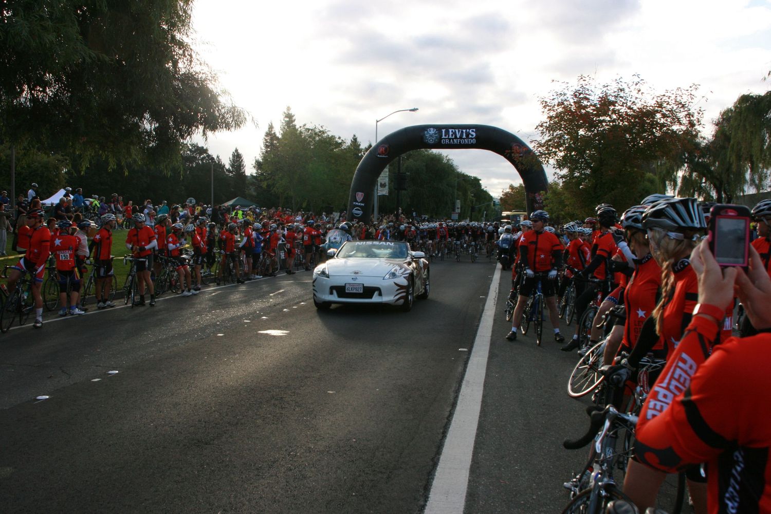 Cyclists lined up under an event arch during a mass participation cycling event.