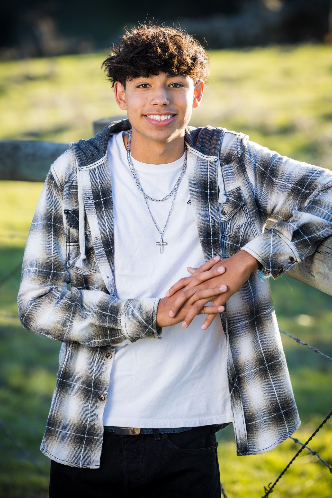 Senior Photos - Outdoor portrait of person wearing plaid flannel shirt and necklace in natural lighting.