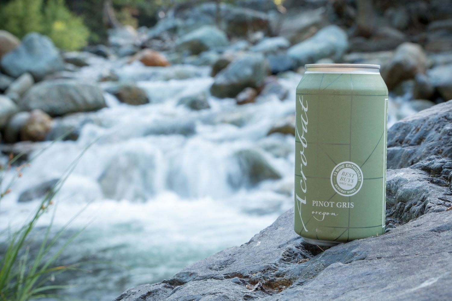Wine can placed on rocky stream with rushing water in background.