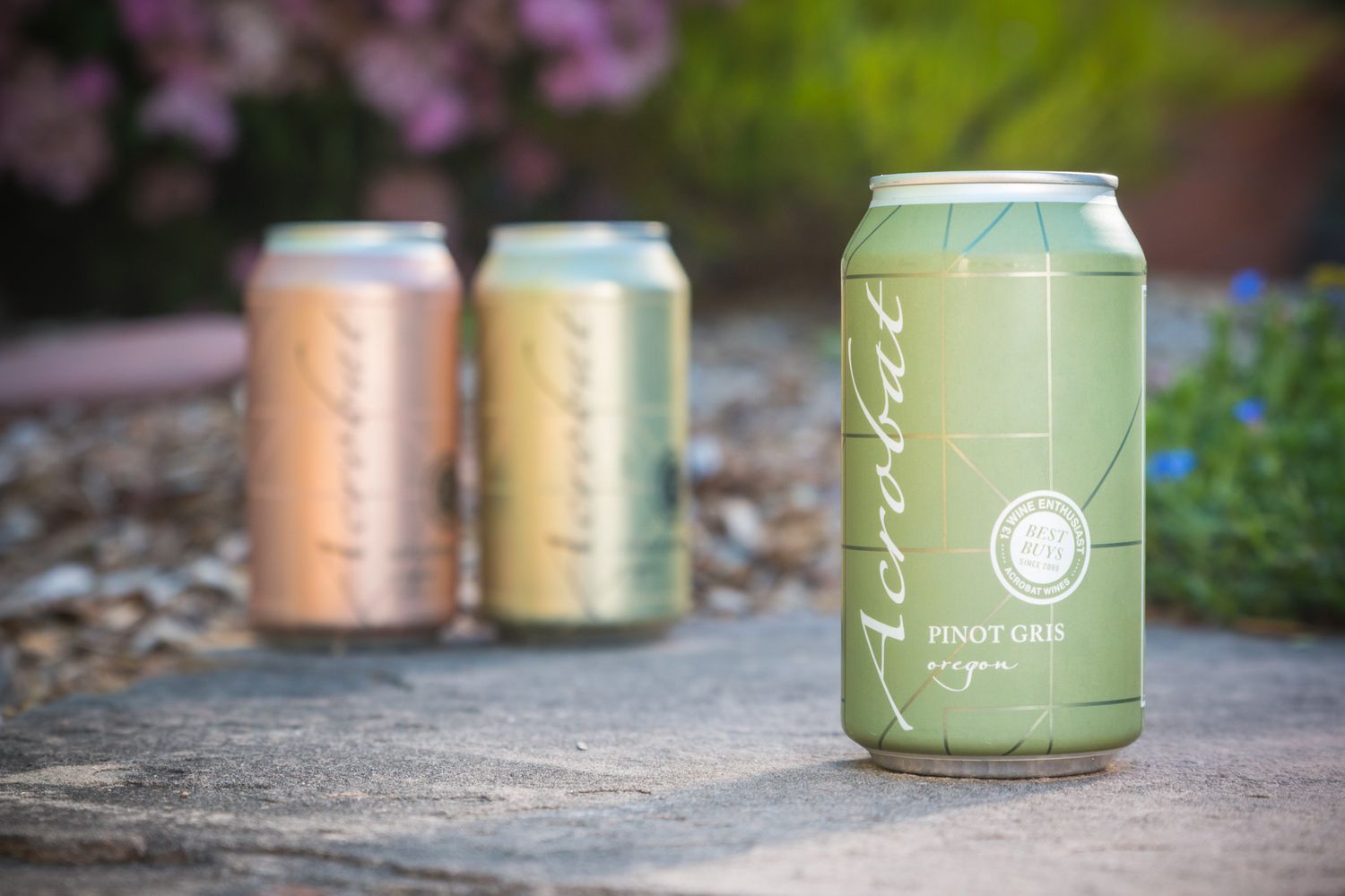 Artisanal canned wines in green and rose gold colors displayed on natural stone.