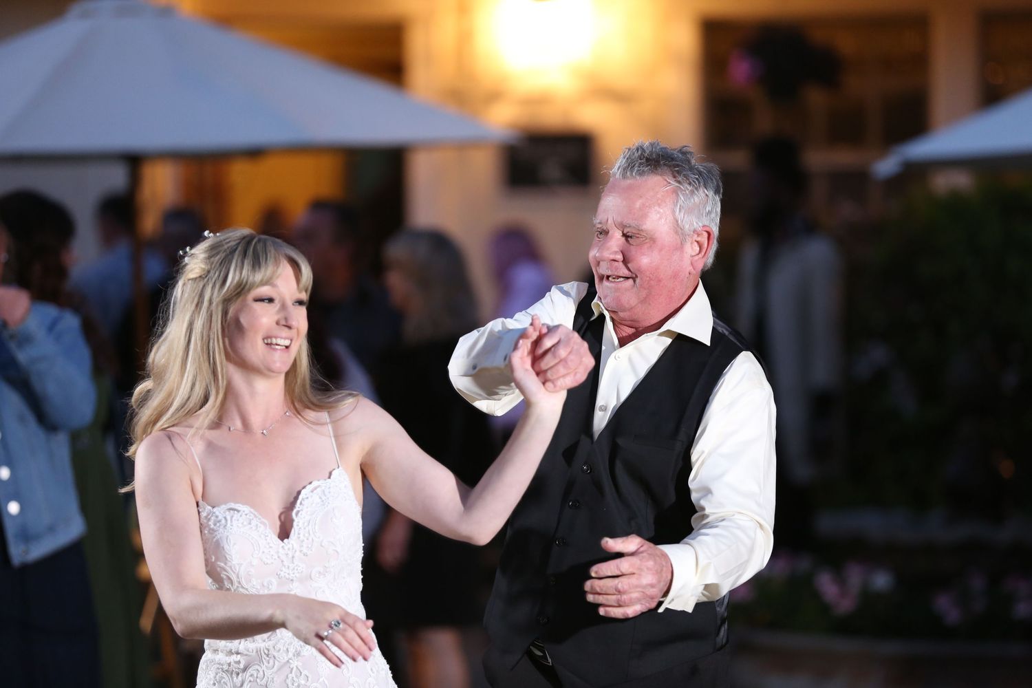 A couple shares a dance at an outdoor evening reception as they celebrate together on the dance floor.