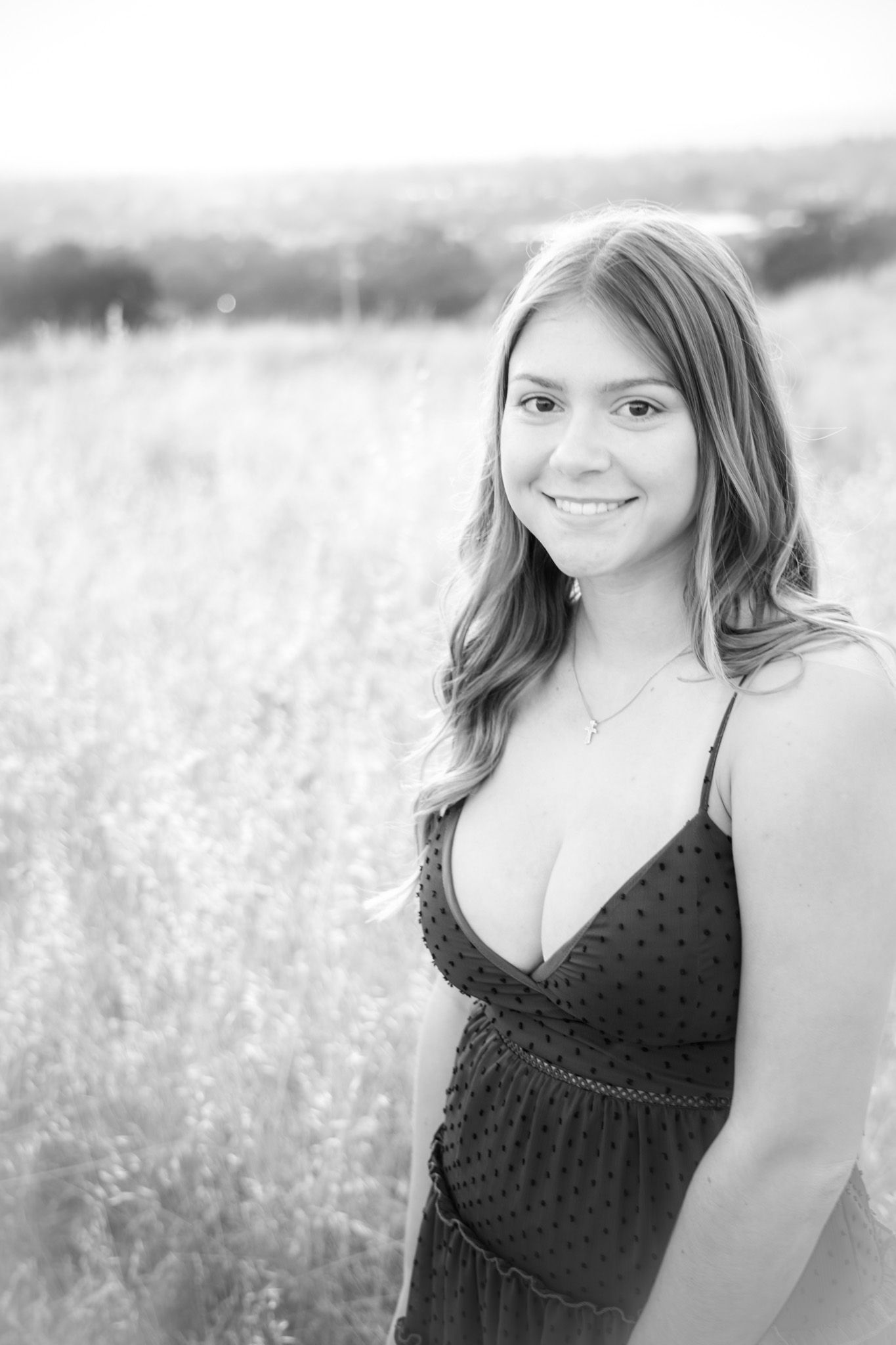 Black and white portrait in dotted summer dress against meadow background.