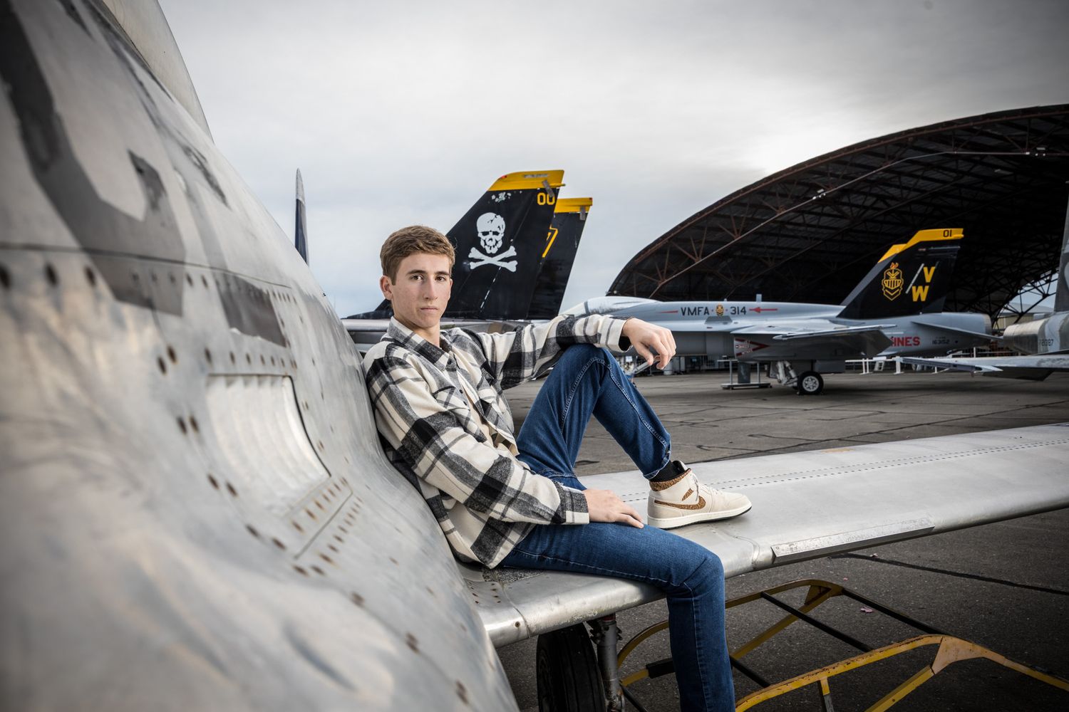 Senior Photos - Side view of military aircraft with person relaxing on fuselage.