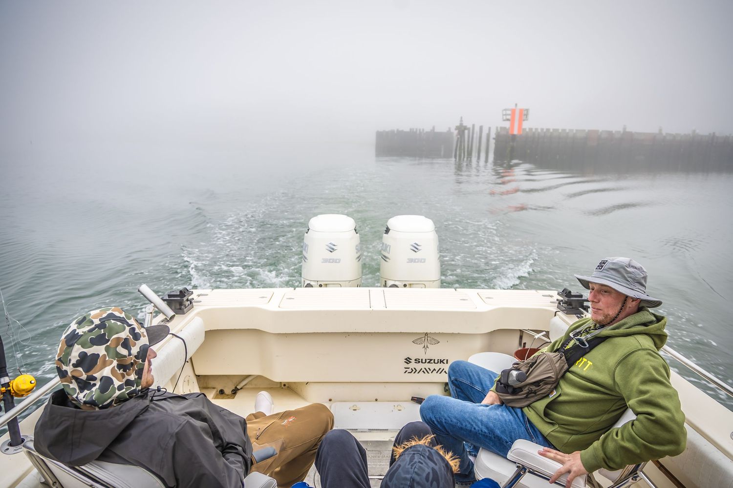Several small open boats navigate through foggy waters while fishing gear and equipment sits on board.