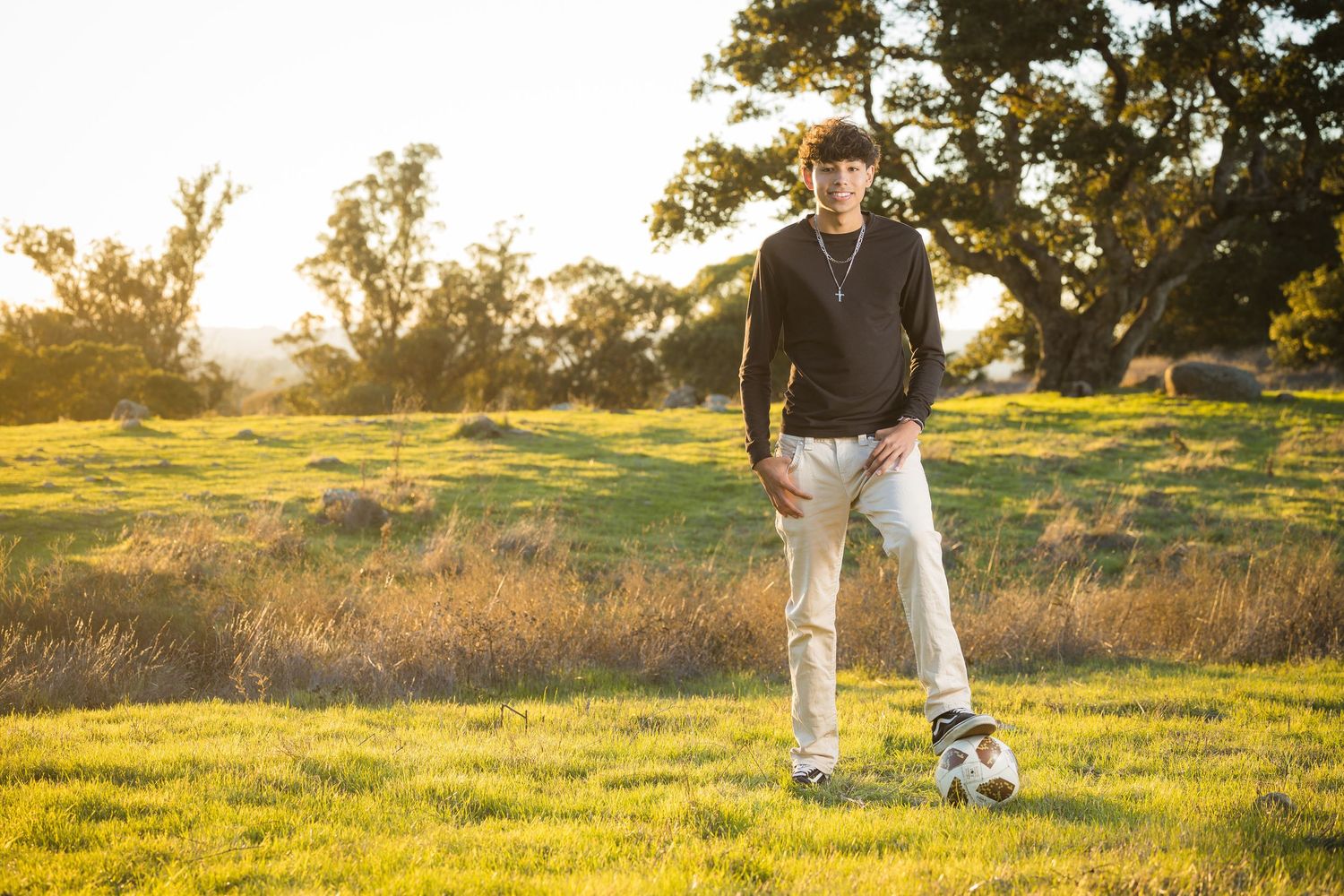 Person in athletic wear standing on grassy field during golden sunset.