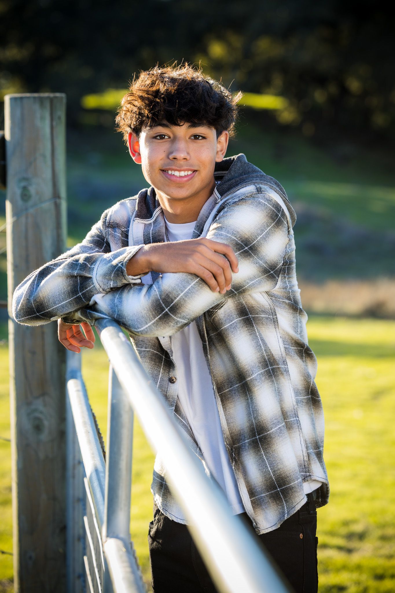 Senior Photos - Person in plaid flannel shirt leaning on metal railing in afternoon sunlight.