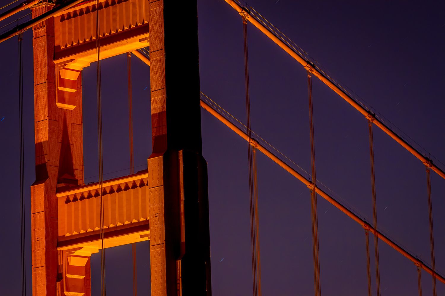 Abstract architectural detail of Golden Gate Bridge tower and cables against purple sky.