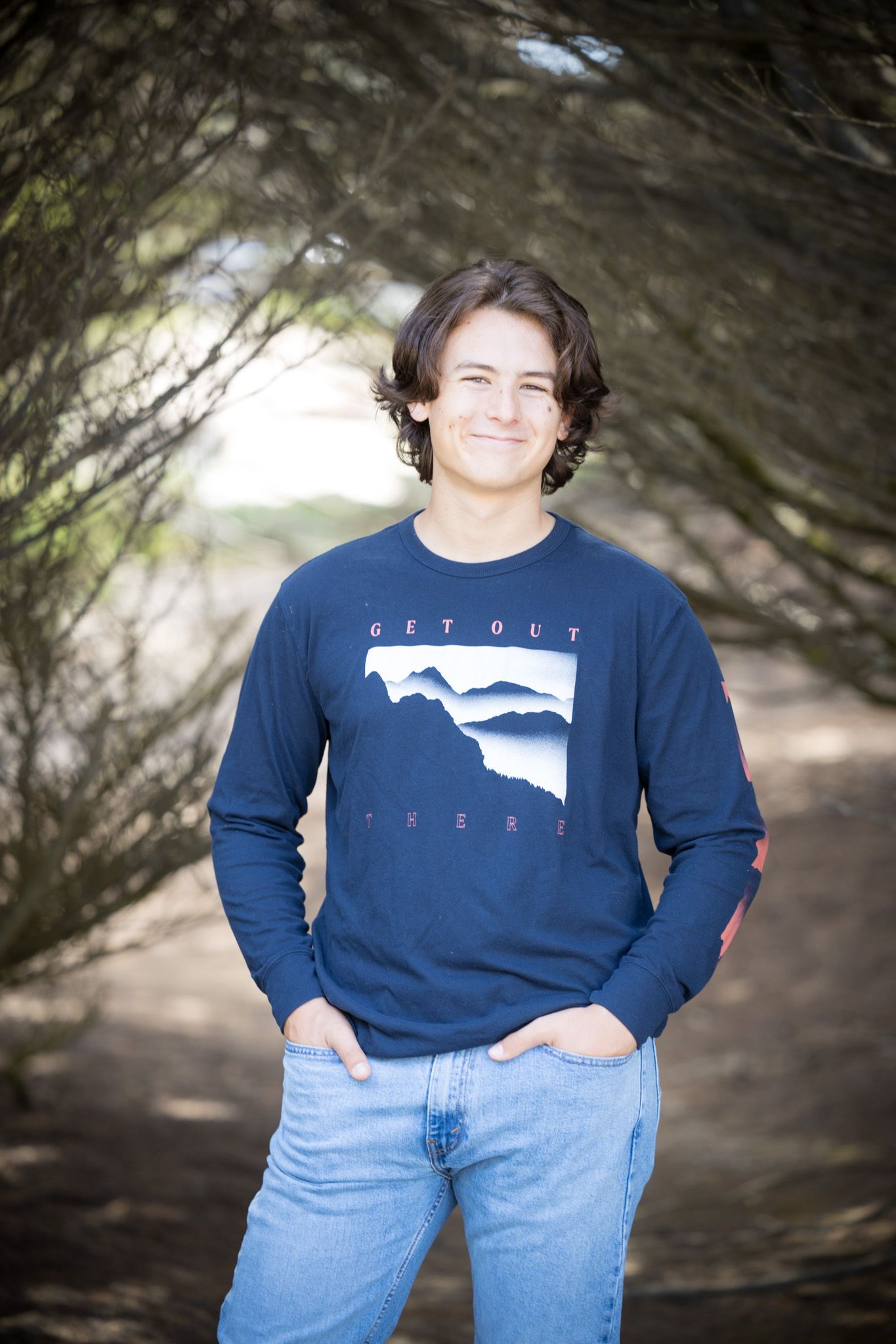 Casual portrait wearing navy graphic sweatshirt and jeans in outdoor setting.