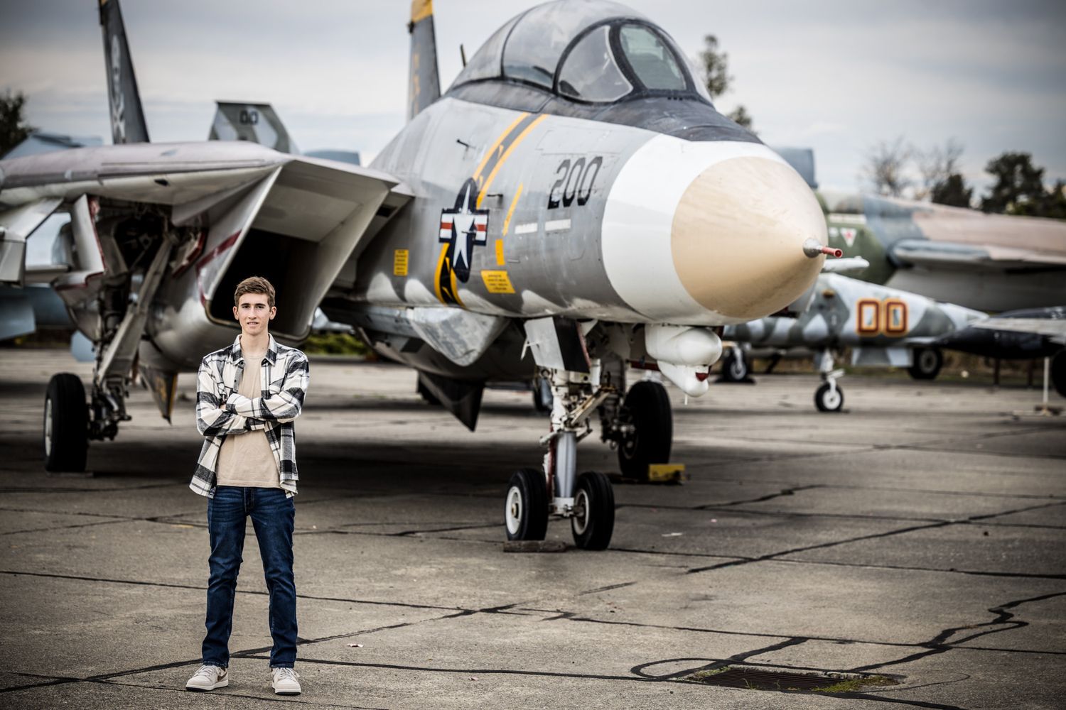 Senior Photos - Standing confidently in front of vintage fighter jet on display.