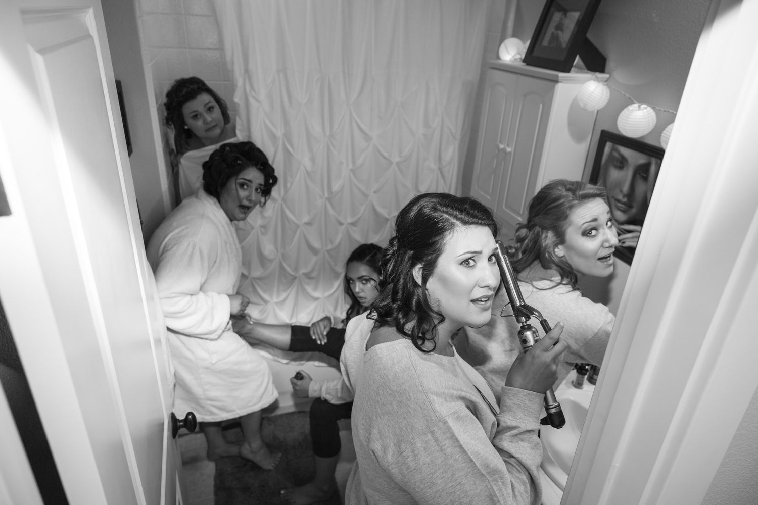 Black and white photo showing people getting ready in a bathroom interior, captured in a candid moment.