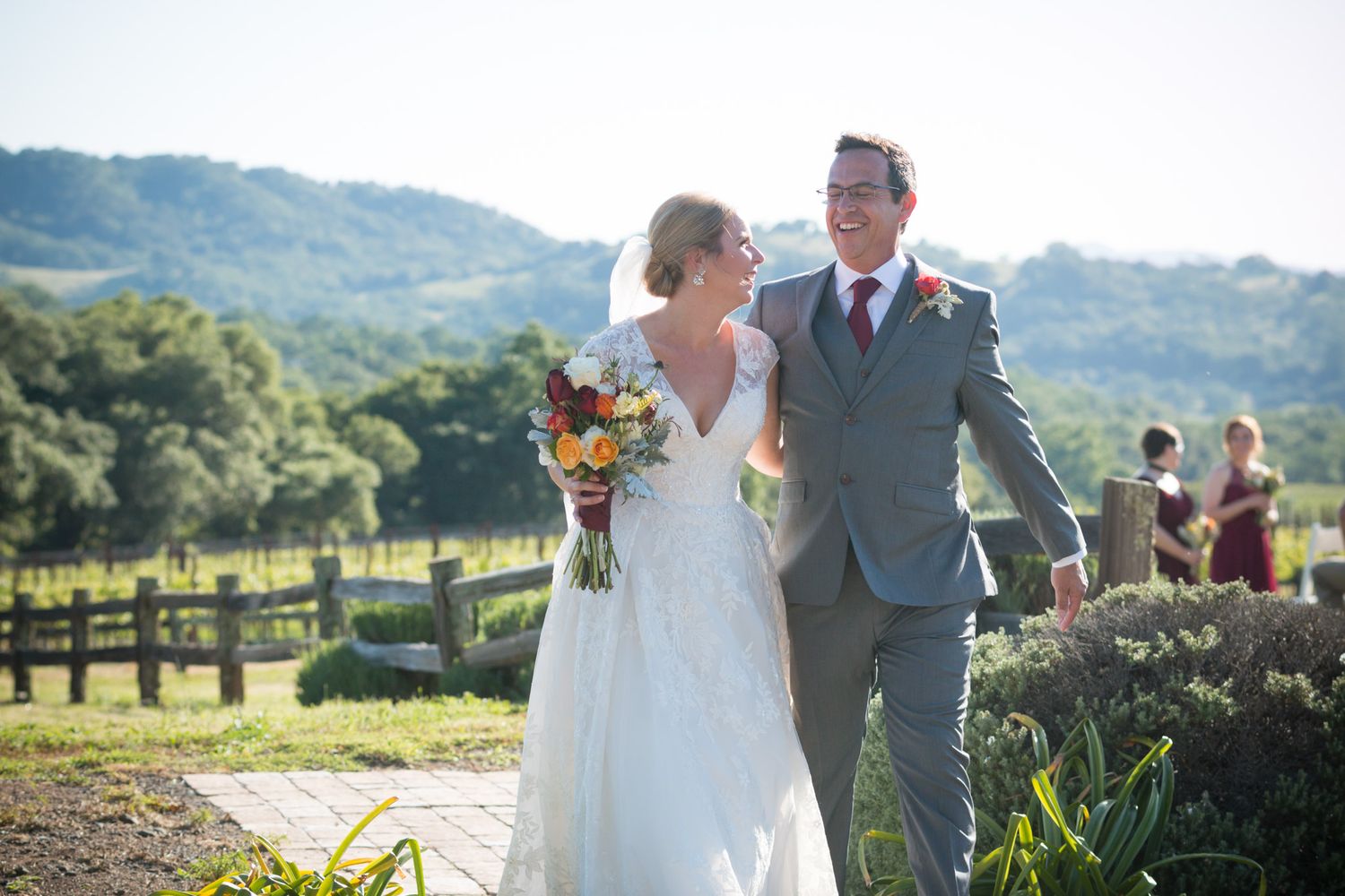Couple celebrating their wedding day at a scenic countryside venue with rolling hills and rustic fences in the background.