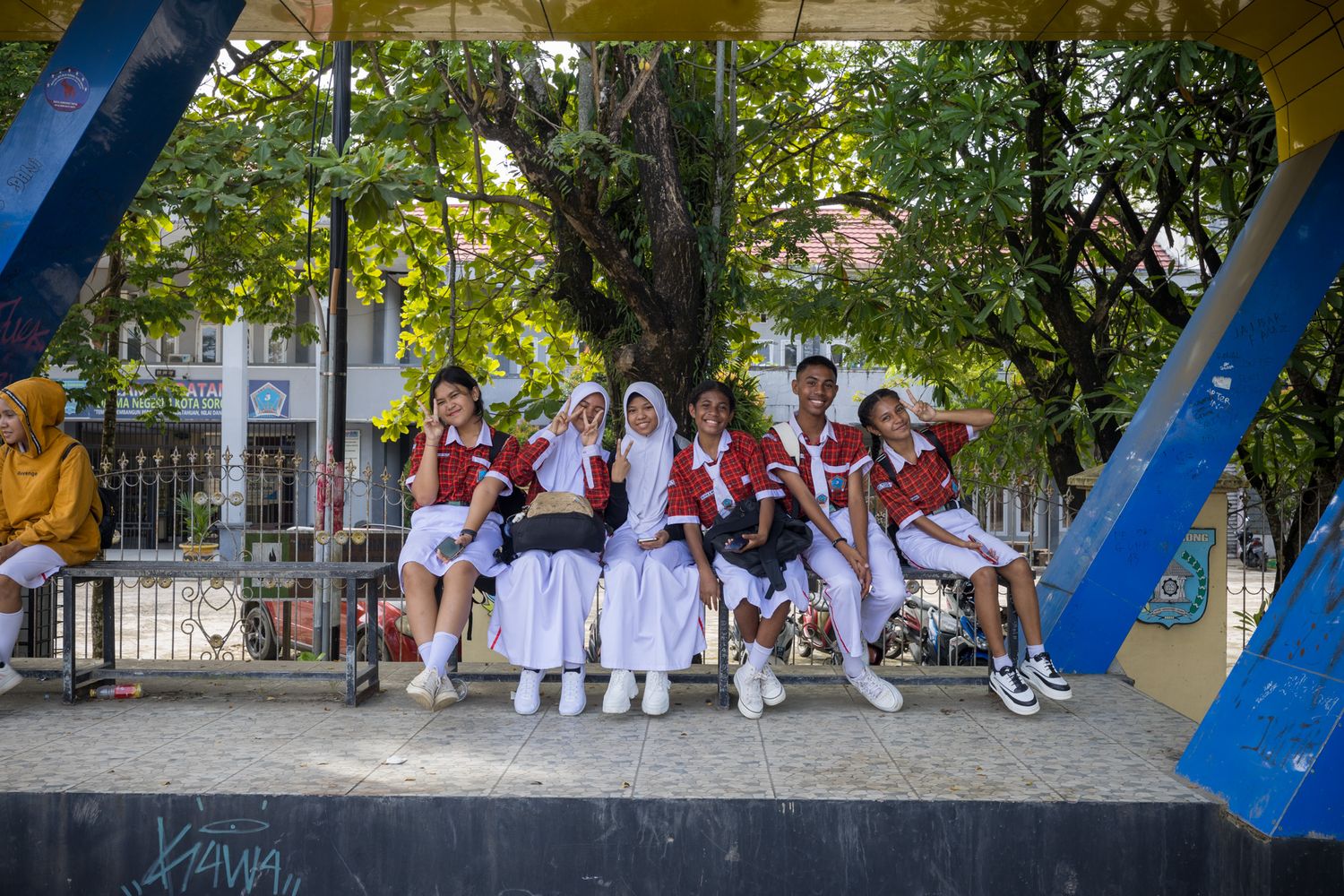 Children in school uniforms playing under yellow and blue shade structures.