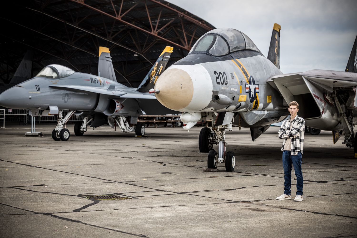 Senior Photos - Military aircraft parked in a hangar with person standing beside huge jet engines.