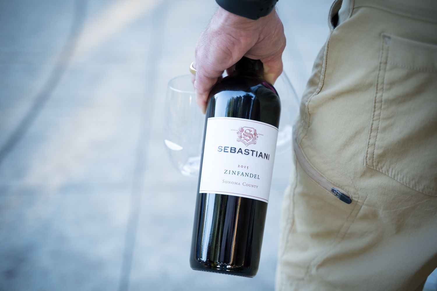 Hand holding a bottle of Sebastiani wine against white background.