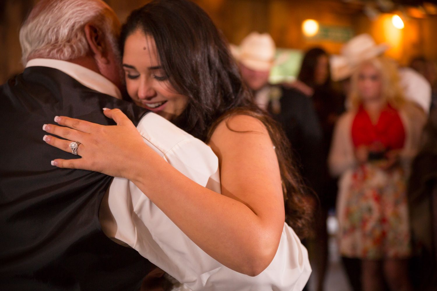 Emotional dance moment between two people at a wedding reception with warm lighting in the background.