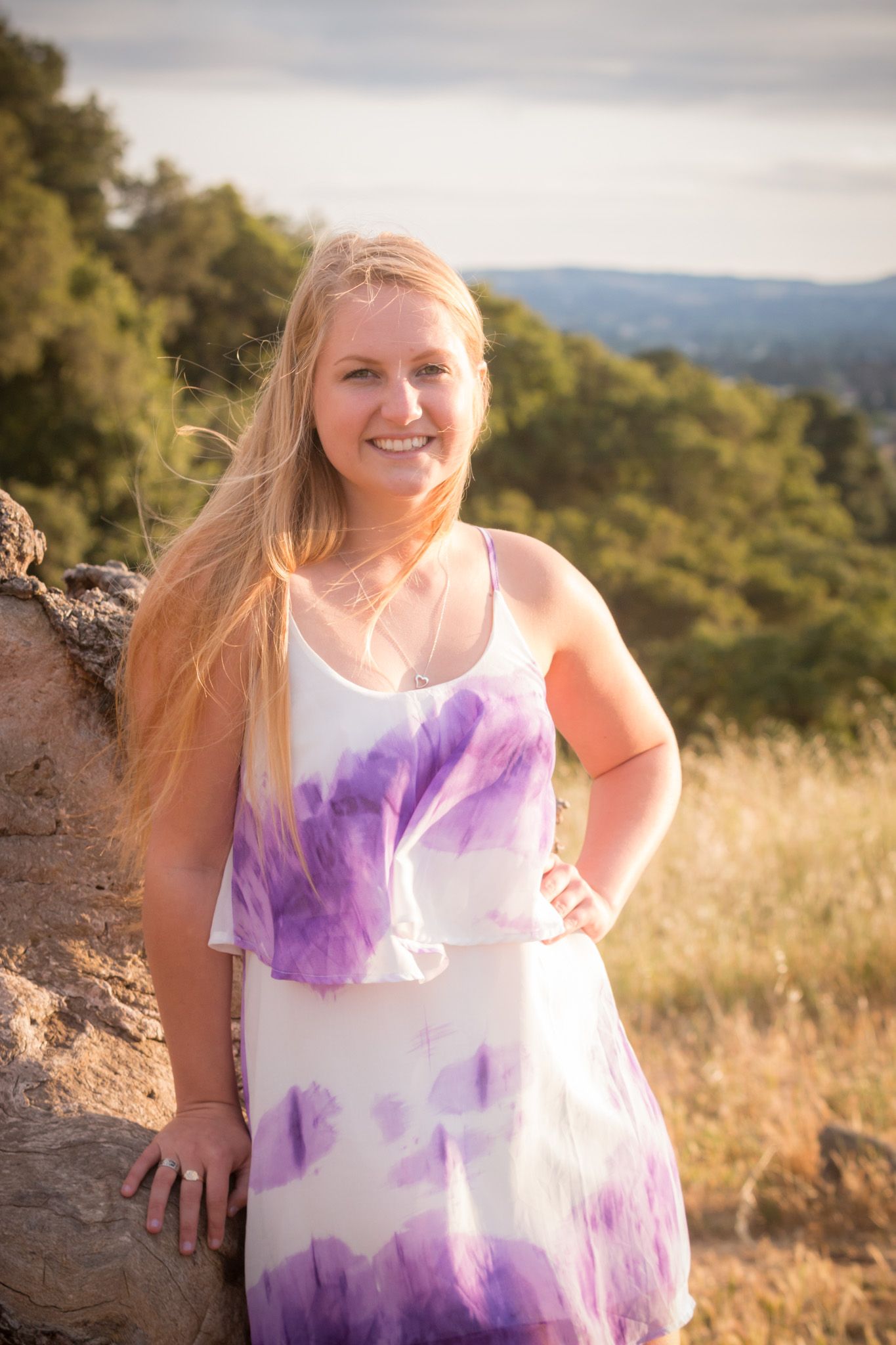 A tie-dye white and purple sundress stands out against a scenic mountain backdrop on a sunny afternoon.