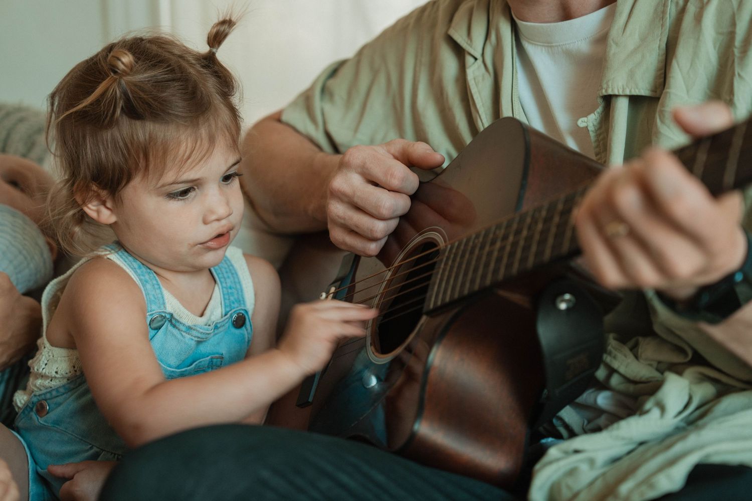 Family bonding time with acoustic guitar on comfortable seating.
