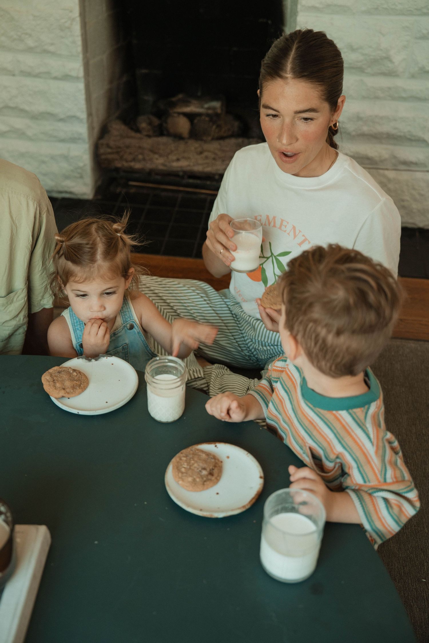 Family gathered around a table enjoying cookies and milk together.
