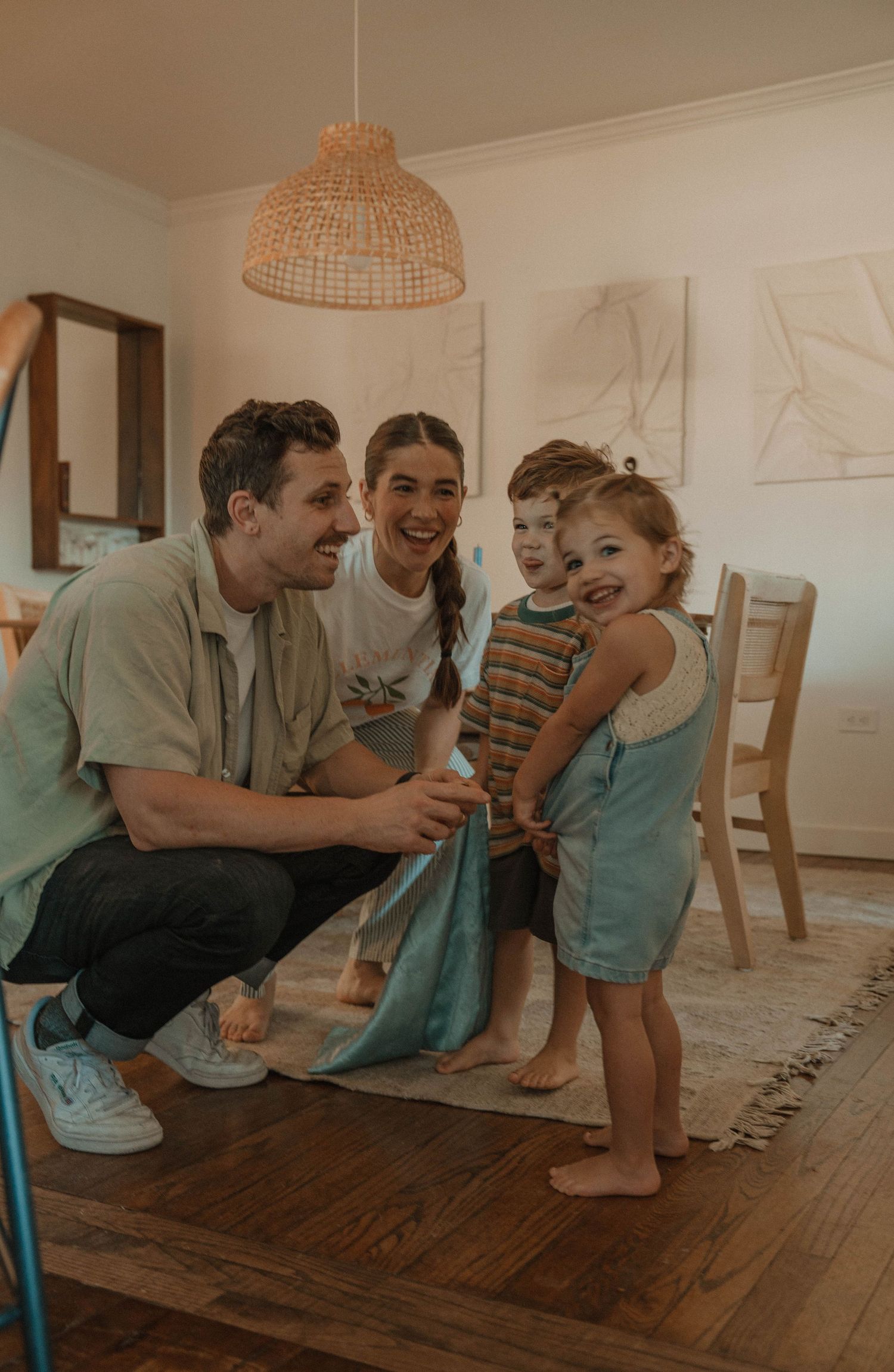 Candid family moments shared on a hardwood floor with woven basket pendant lights overhead.
