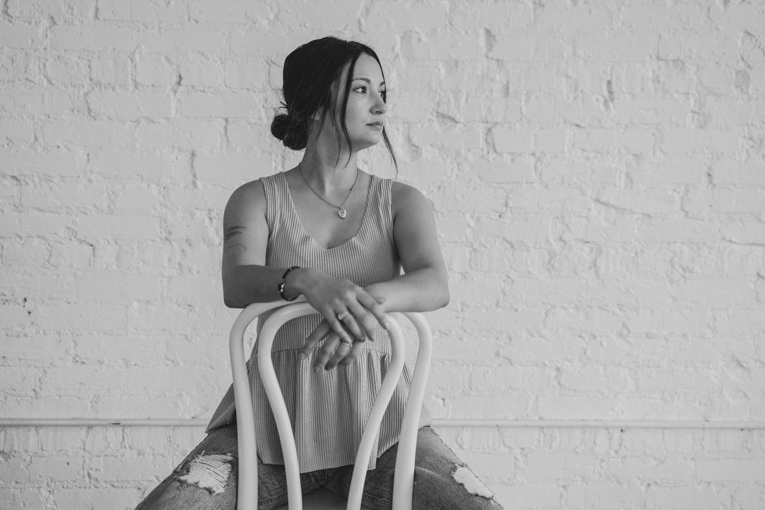 Minimalist portrait series featuring white brick wall and wooden chair.