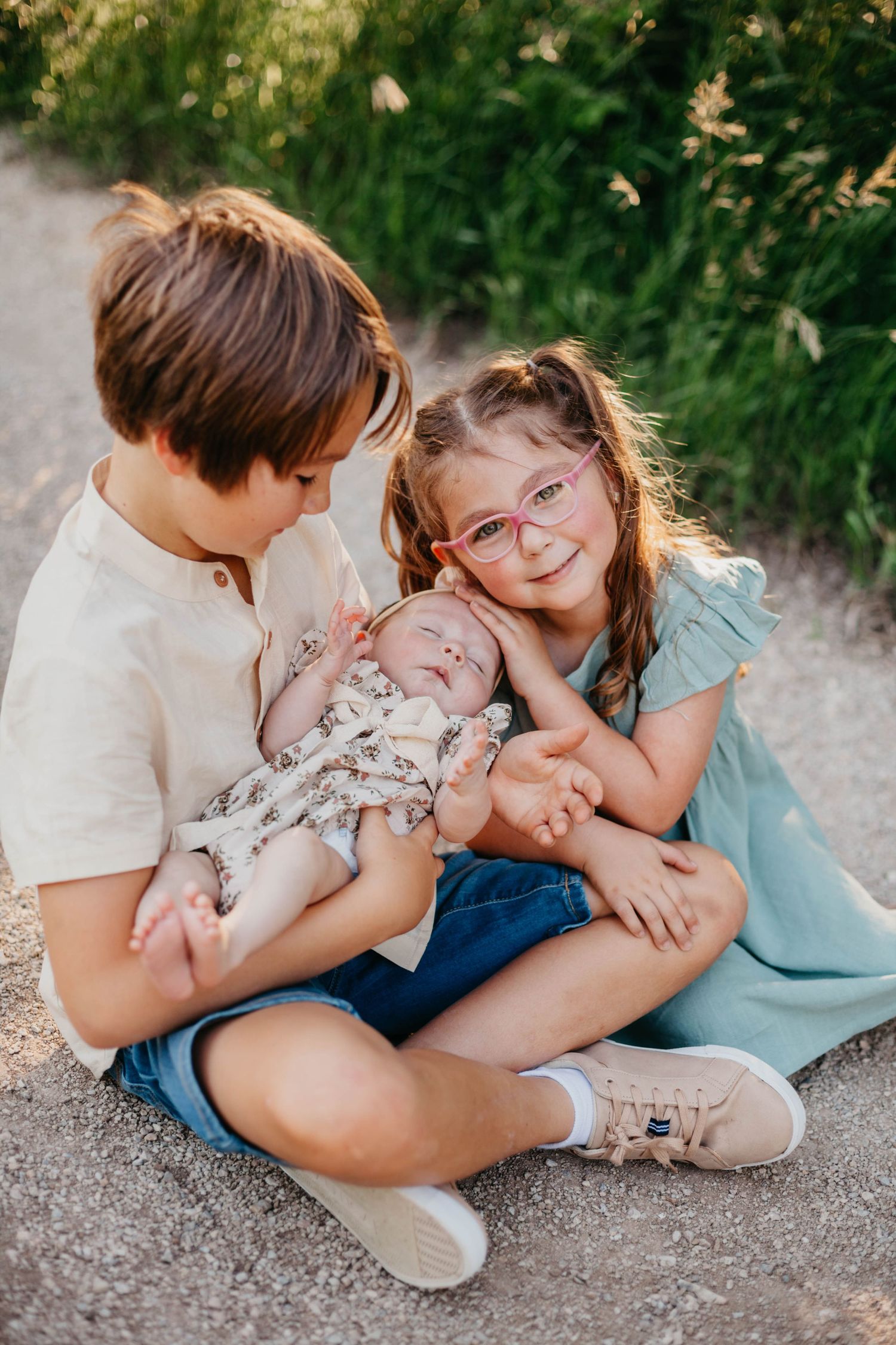 Family enjoying tender moments together while sitting on ground during golden hour sunset.