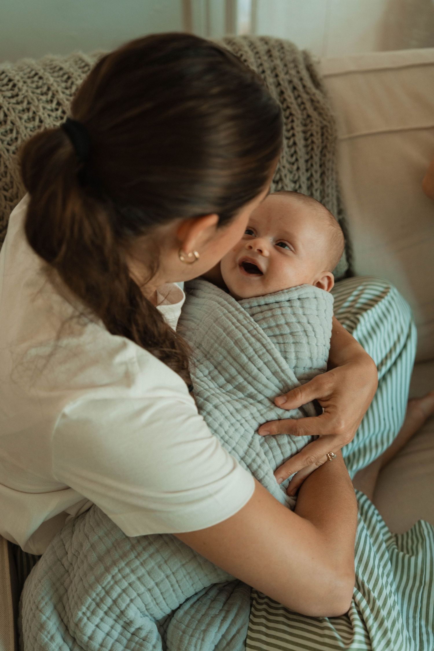 Tender family cuddles and embraces on a light-colored couch.