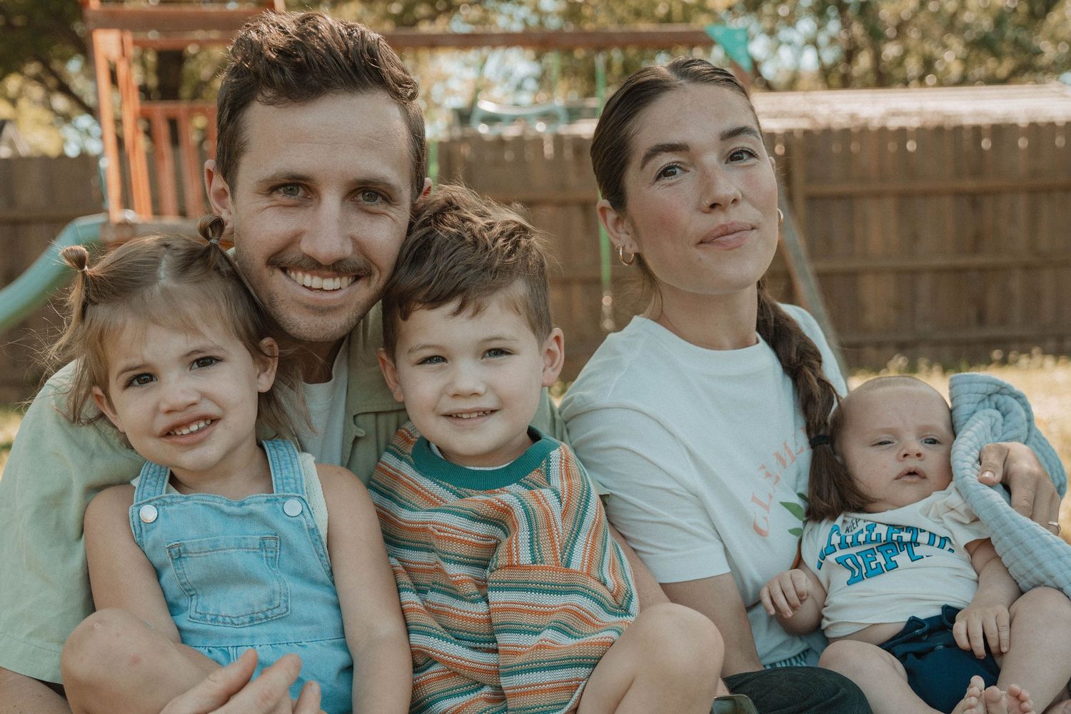 Family portrait in coordinating turquoise and neutral tones outdoors.
