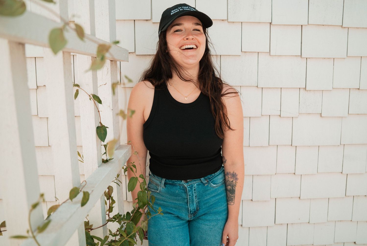 Casual portrait session against white shingle wall with natural greenery.