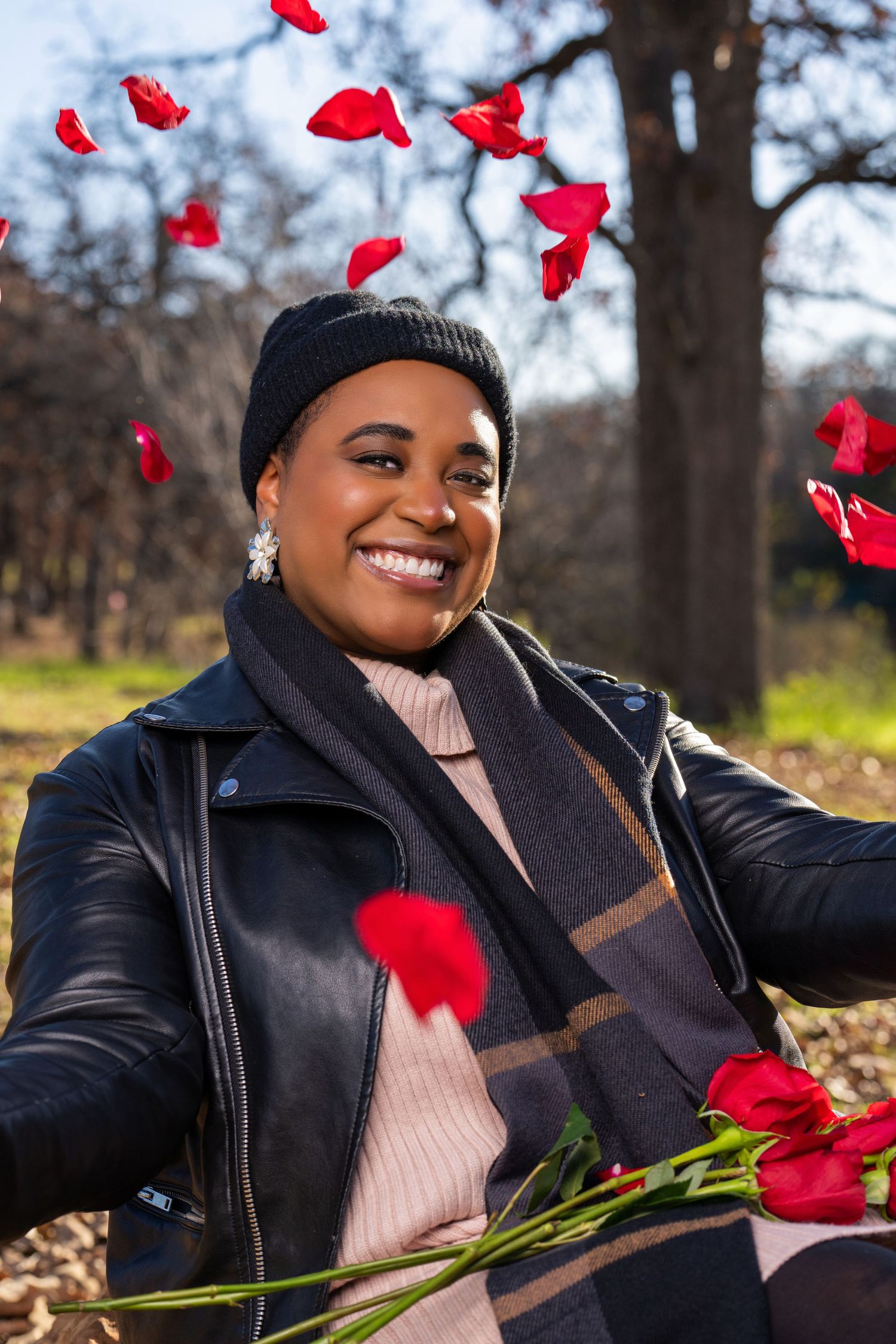 Joyful winter portrait with flying red rose petals in leather jacket.