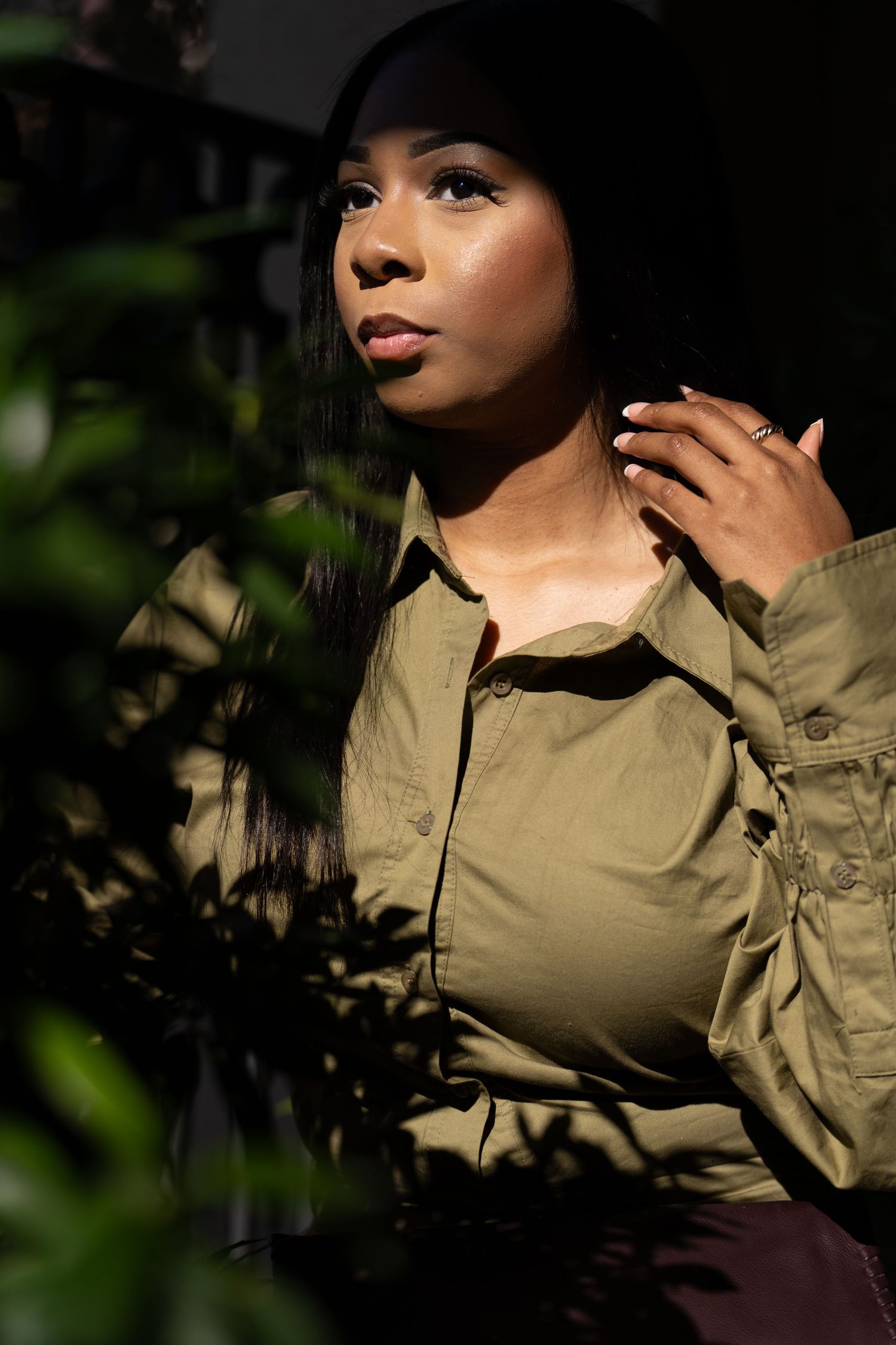 Atmospheric portrait in natural lighting with a khaki shirt and black cap.