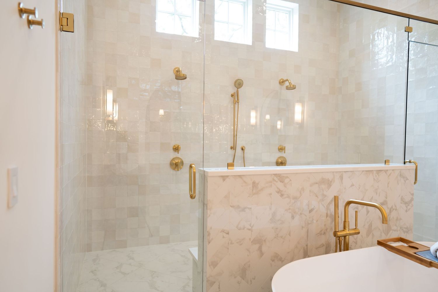 Luxurious marble bathroom with glass shower enclosure and gold fixtures featuring elegant white and beige tones.