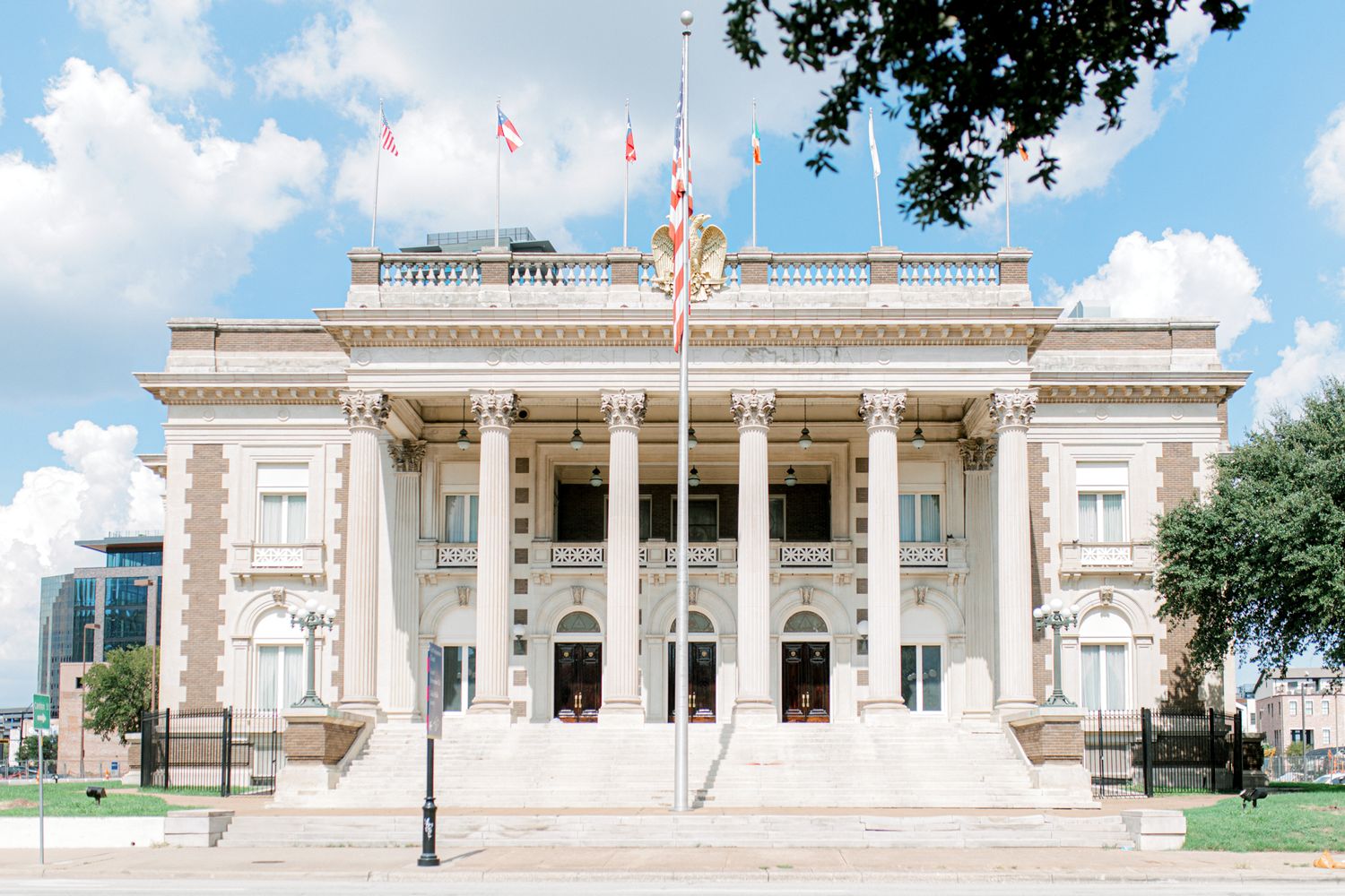 A grand neoclassical courthouse building with white columns and American flags flying on its facade stands in Texas.
