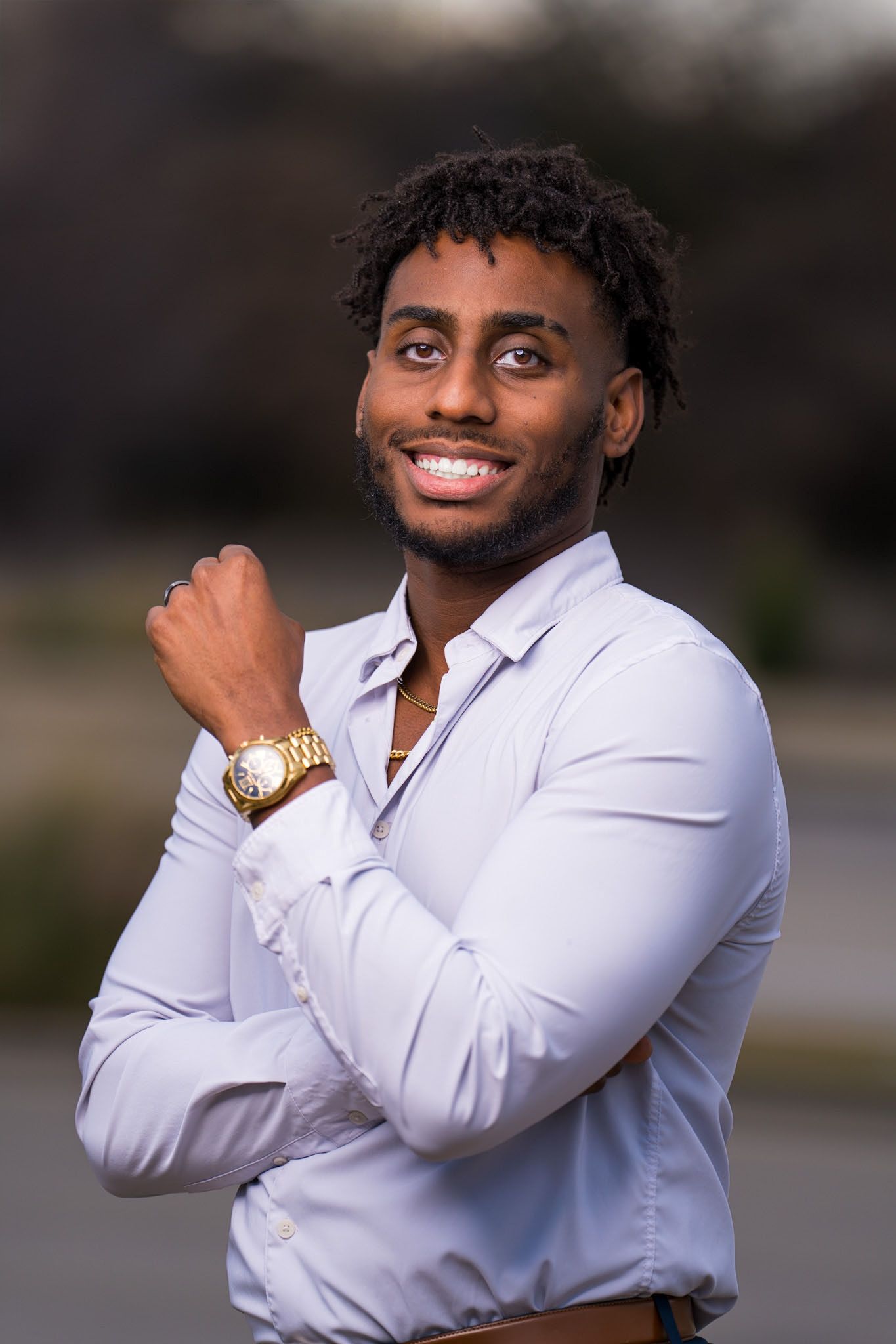 Professional headshot featuring white button-down shirt and gold watch.