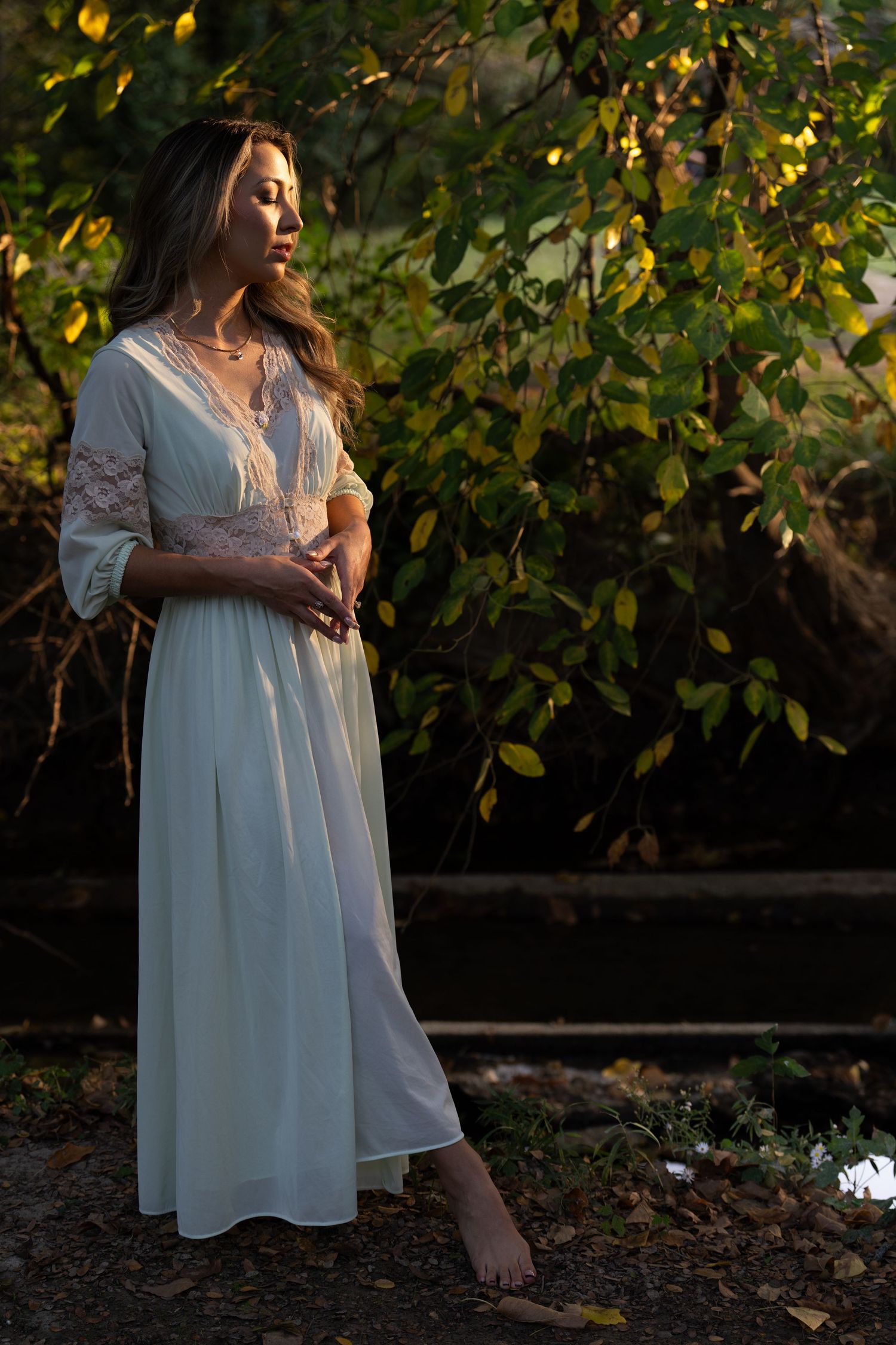 Ethereal portrait in white flowing dress against autumn foliage at golden hour.