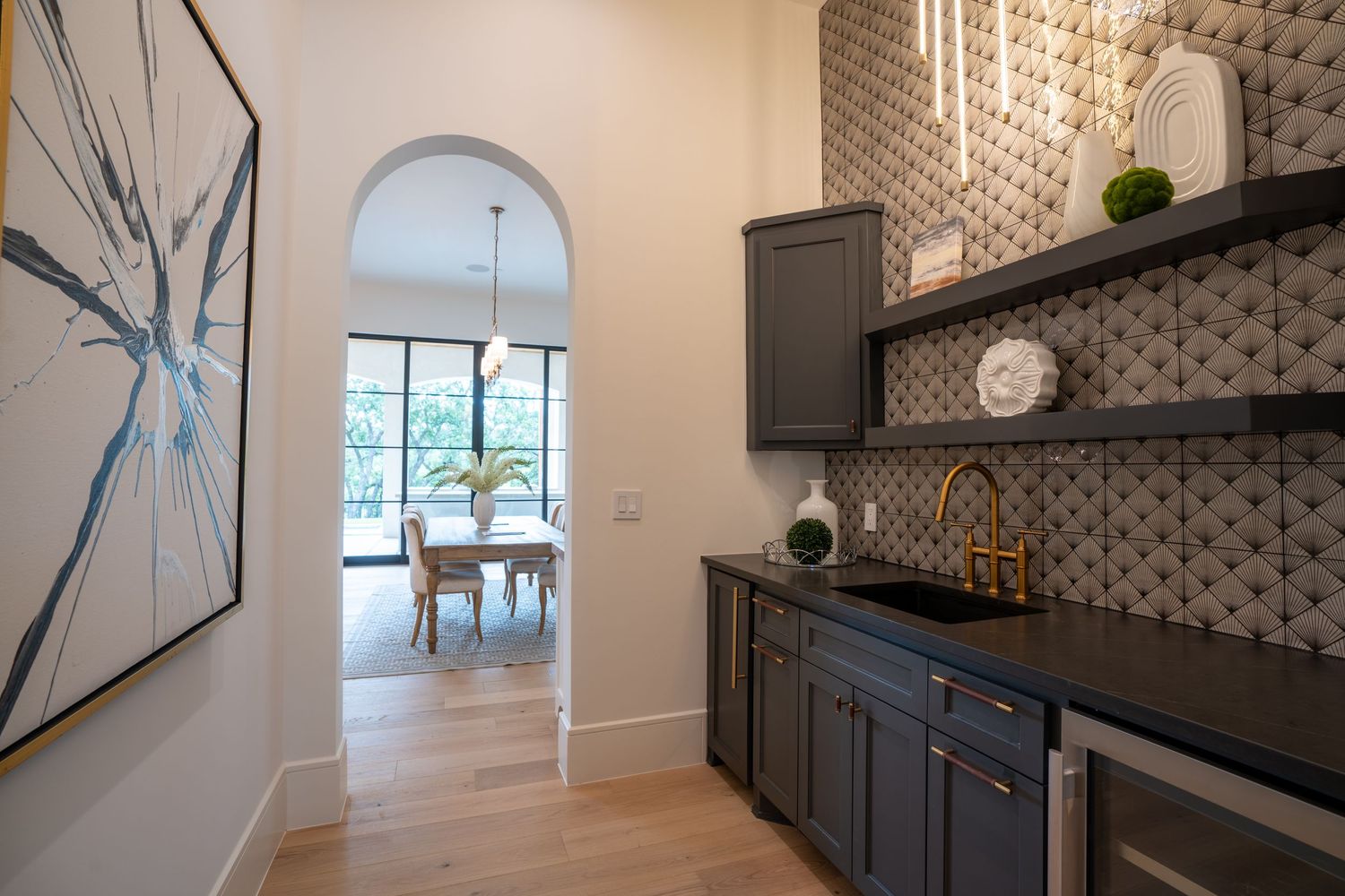 Stylish butler's pantry with dark cabinets, patterned backsplash and modern artwork.