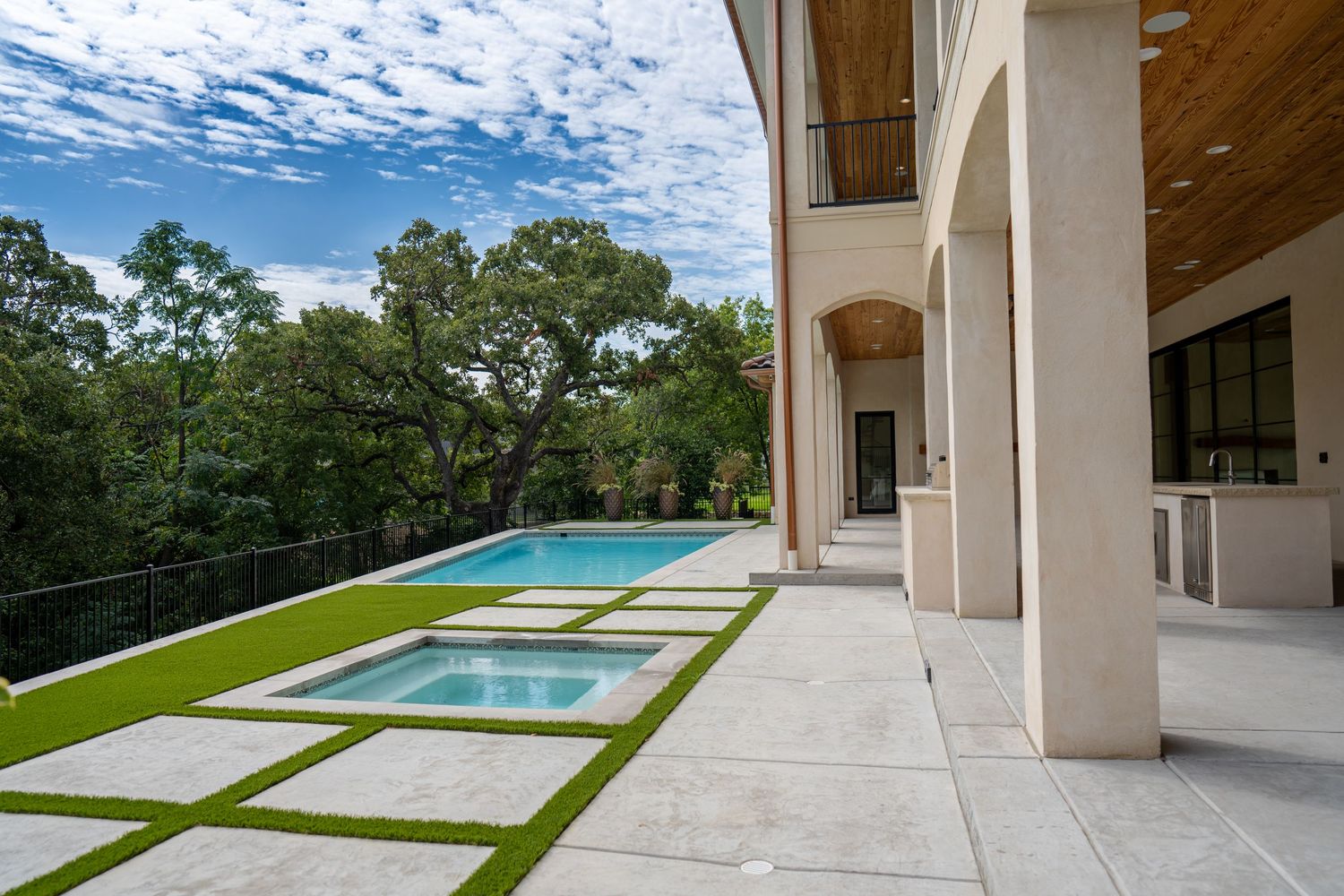 Modern infinity pool and spa with geometric concrete pavers on a hillside terrace.
