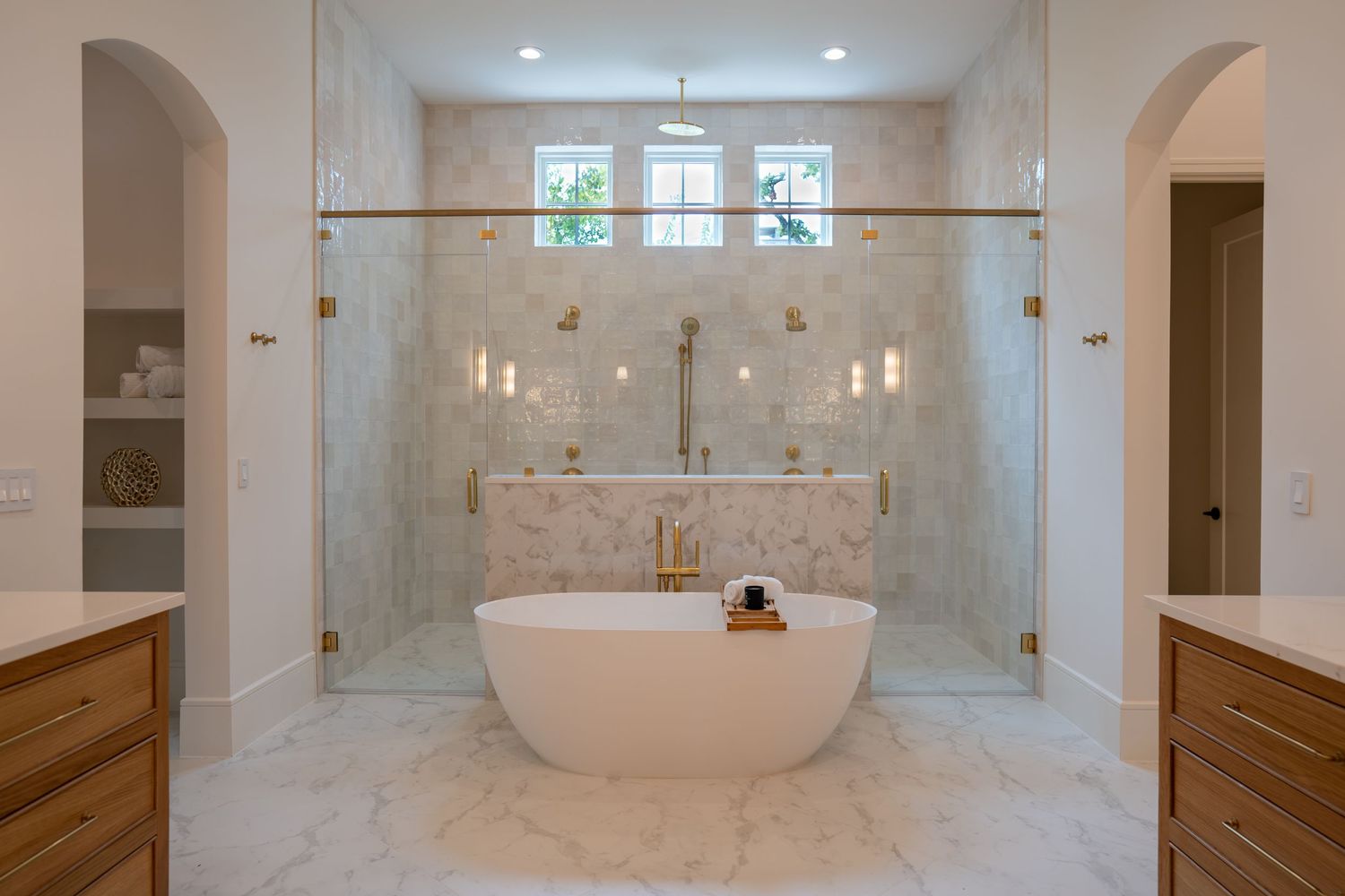 Spacious master bathroom with freestanding tub, marble walls, and glass-enclosed shower area.