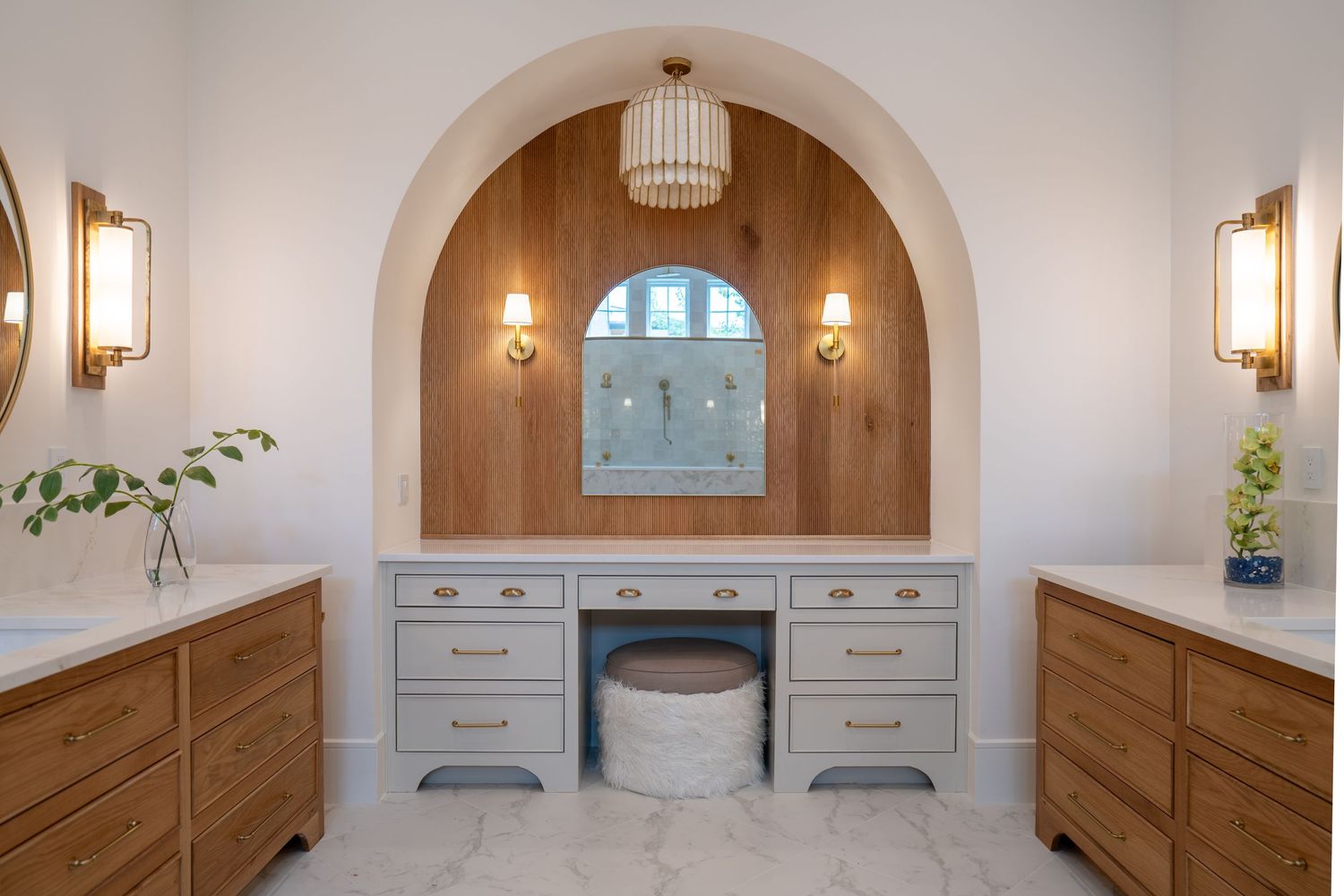Elegant vanity nook with arched design, built-in makeup station, and pendant lighting.