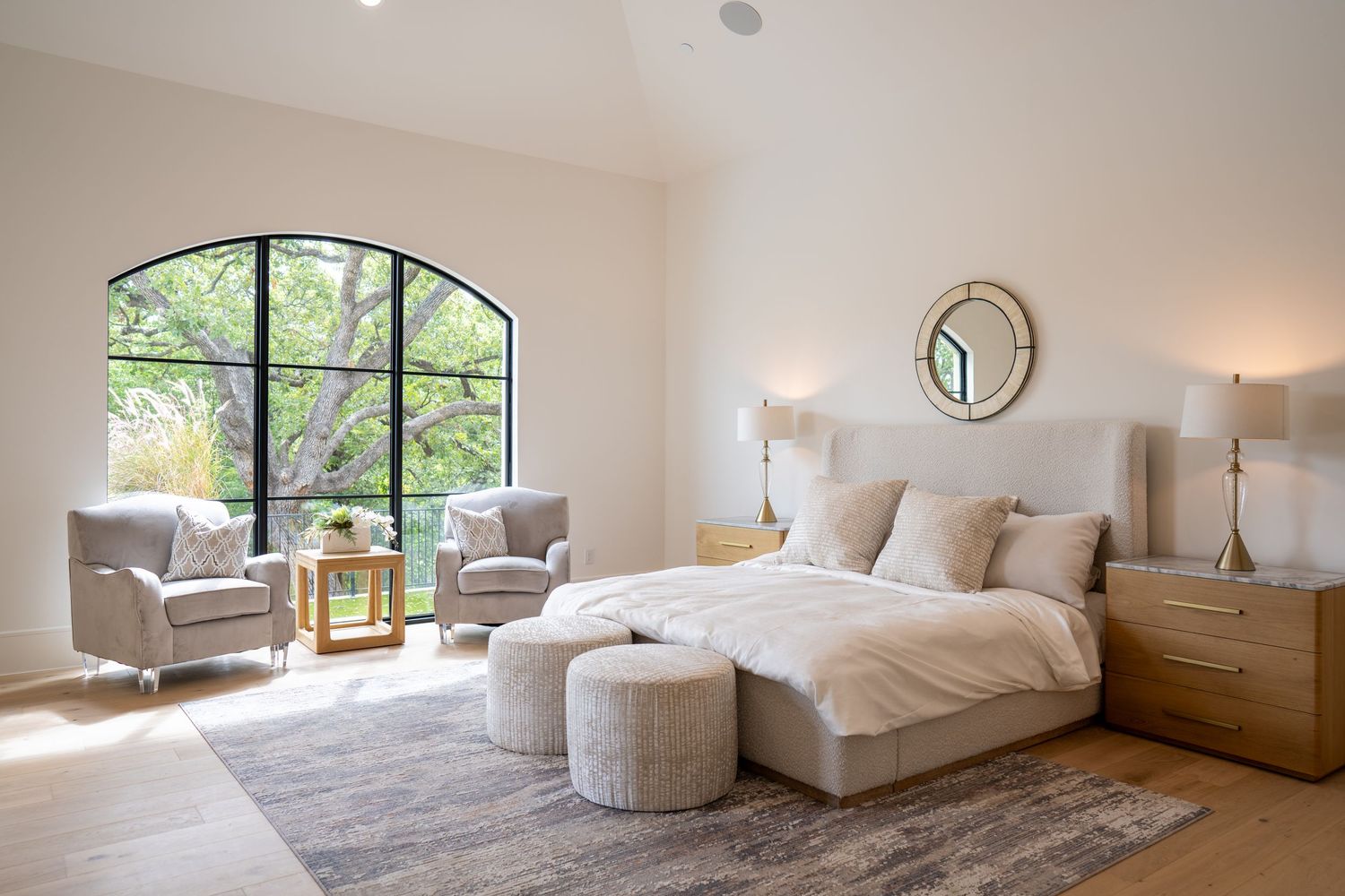 Serene bedroom with arched windows, neutral decor and modern light fixtures.