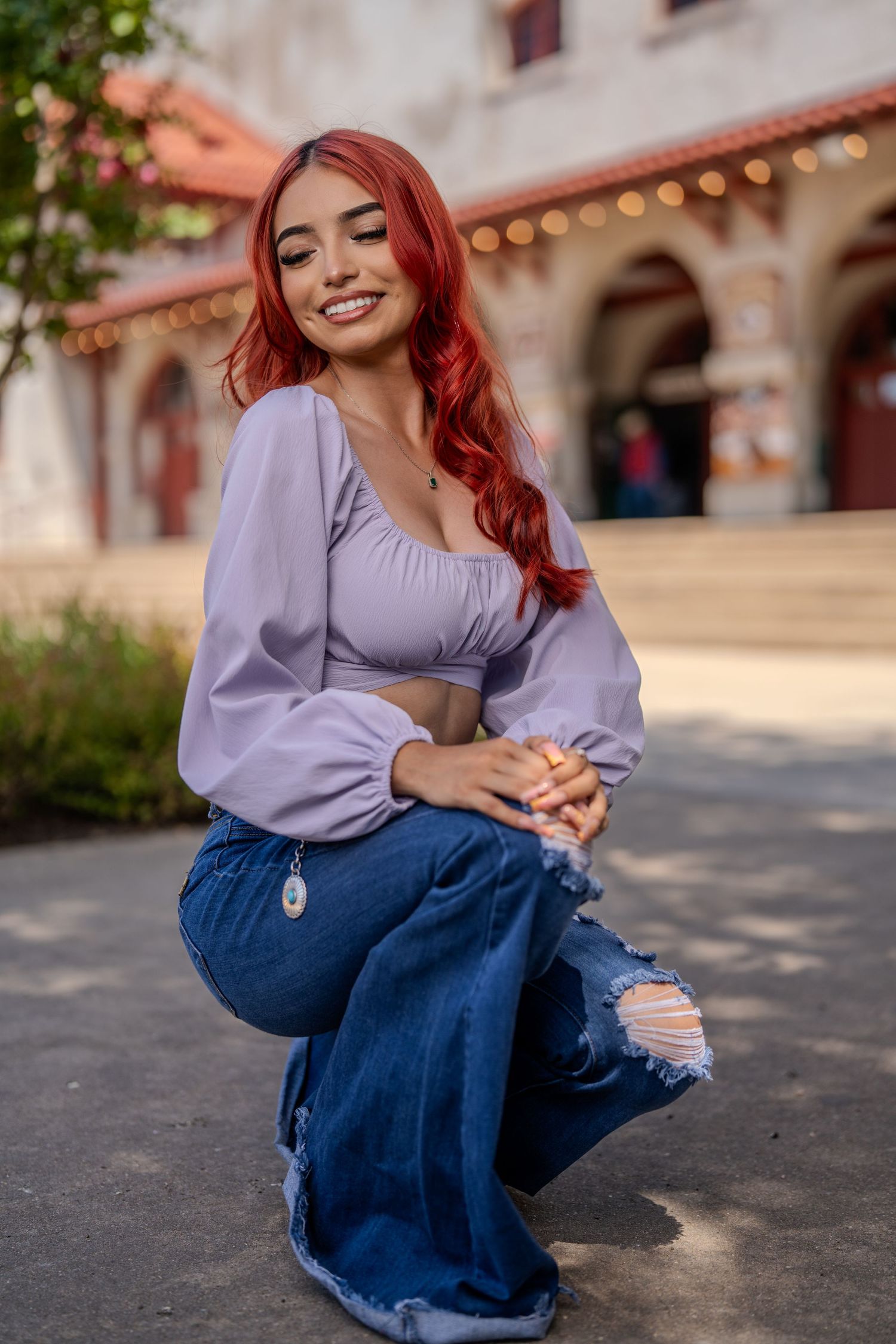 Fashion portrait featuring purple crop top and distressed jeans against Spanish architecture.