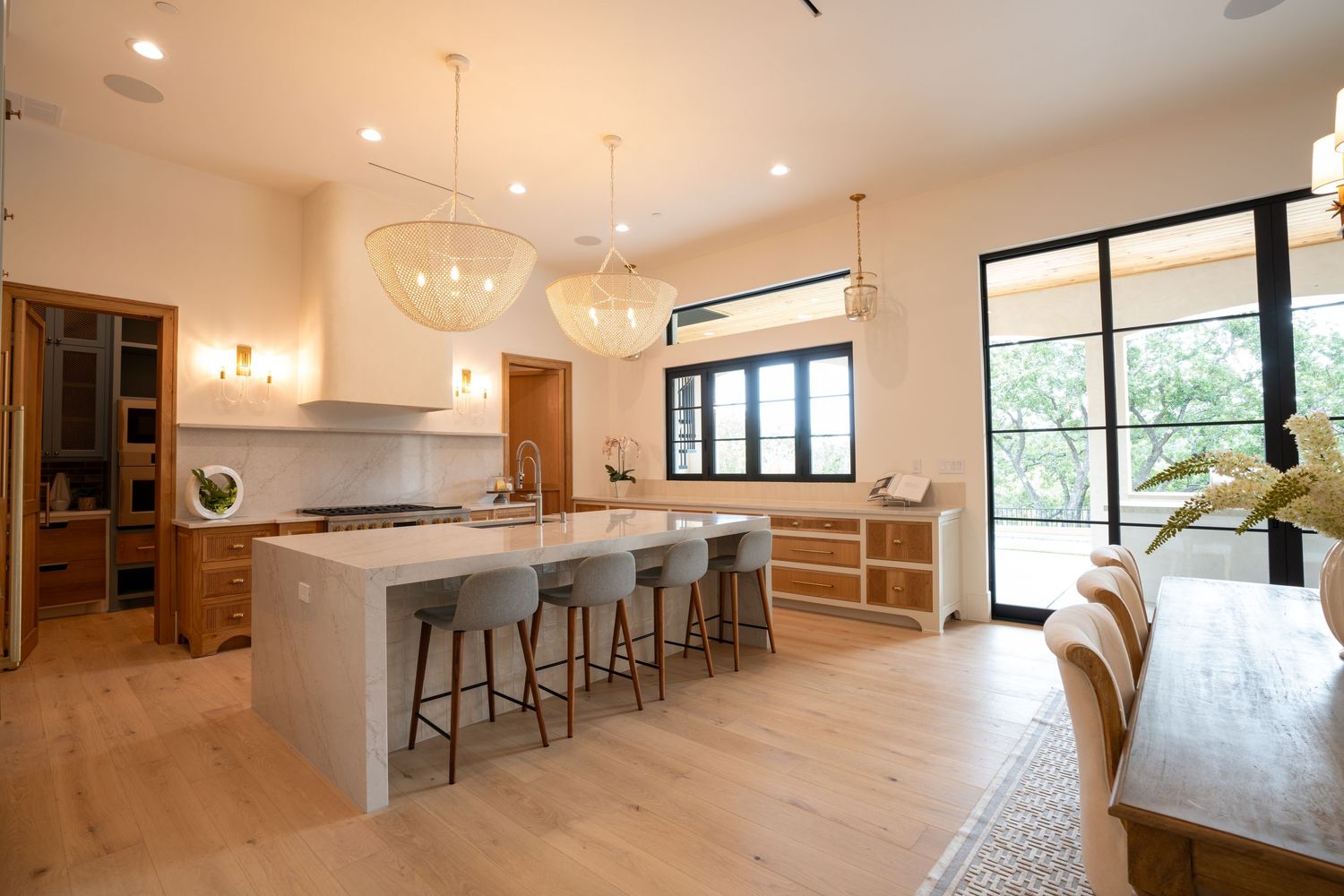 Modern open concept kitchen with light wood floors, concrete island and globe pendant lights.