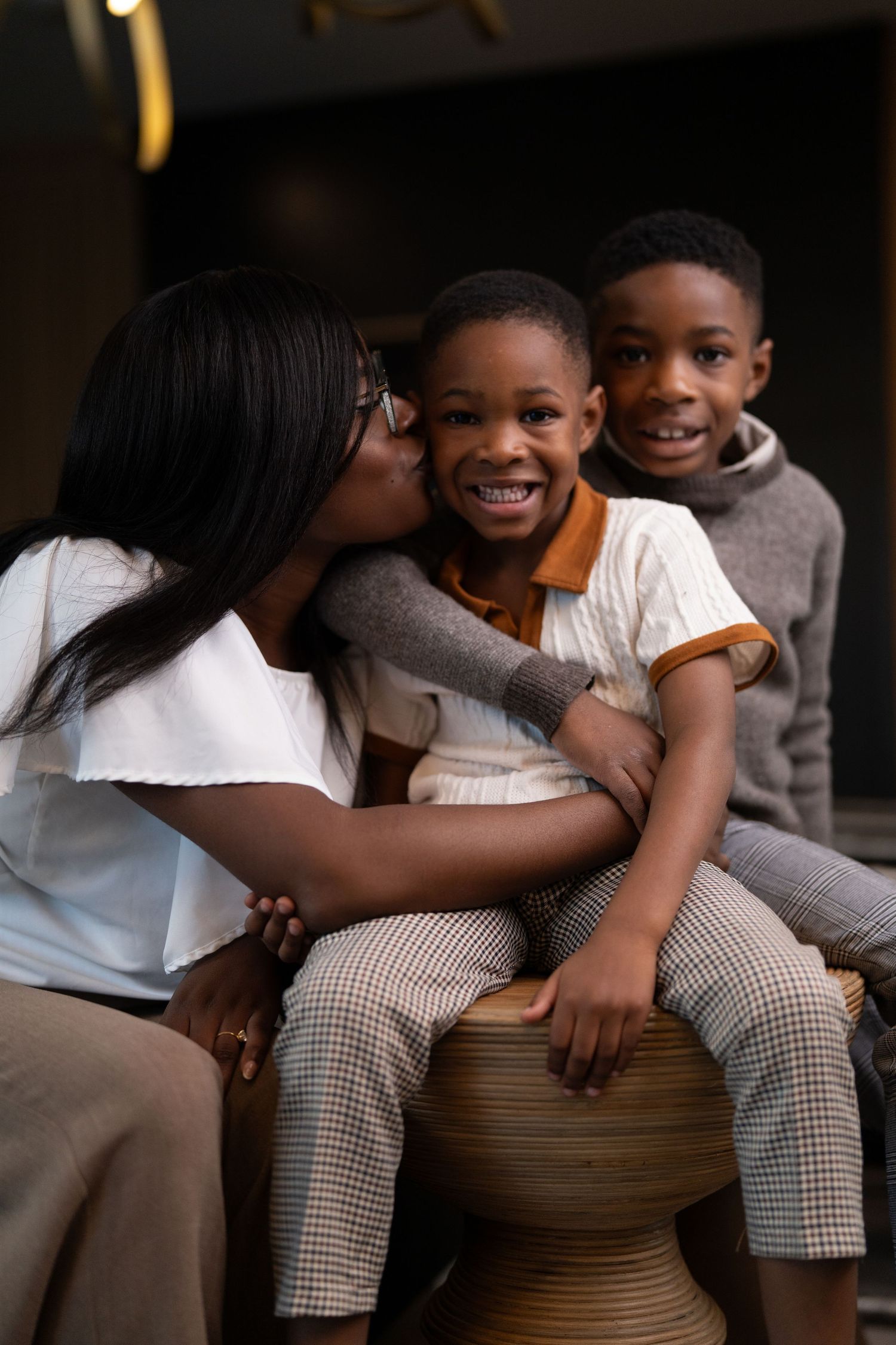 Three people share an affectionate moment while sitting together in modern home setting.
