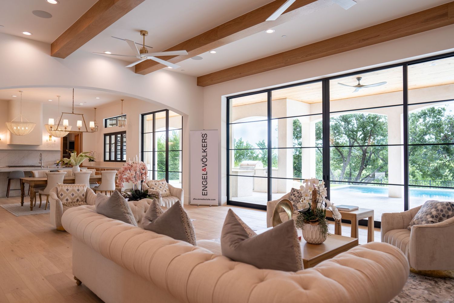 Open concept living space with exposed beams, large windows, and plush sectional sofa.