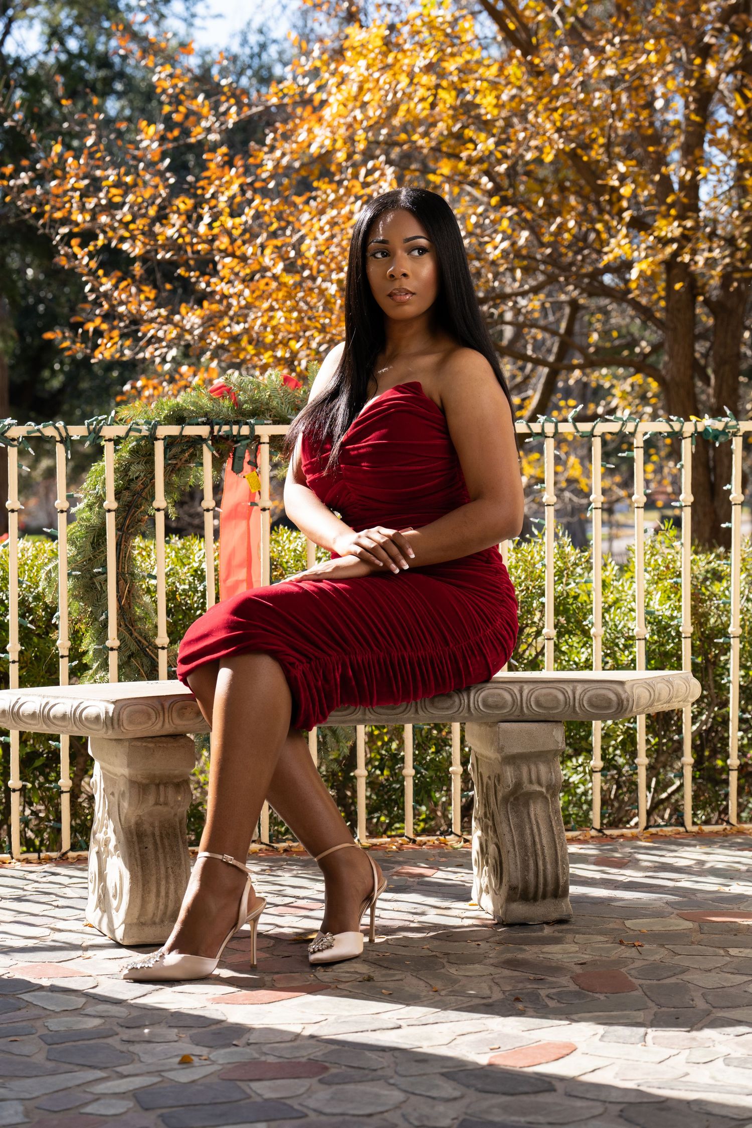 A series of outdoor portraits in a crimson dress against autumn foliage and white railings on a sunny day.