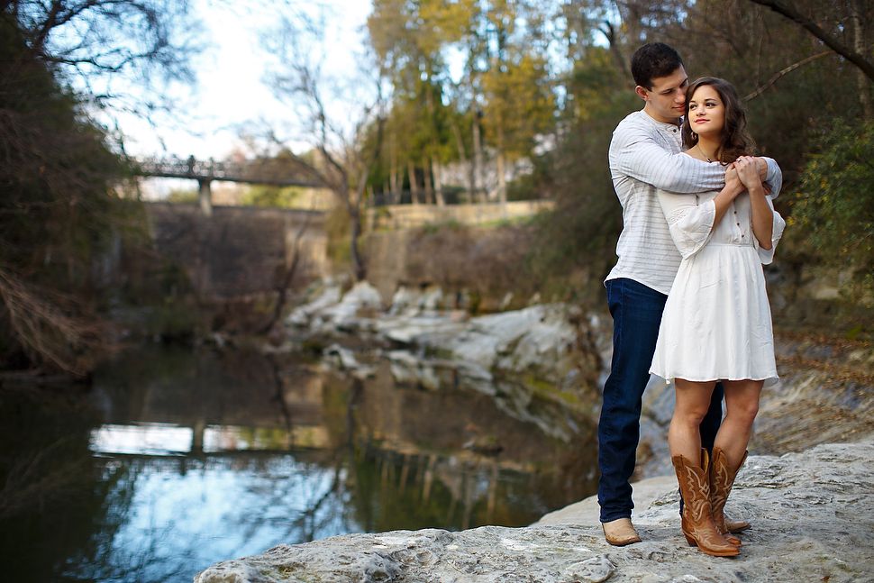 A couple shares a tender moment during a riverside photoshoot at sunset on a tranquil autumn day.