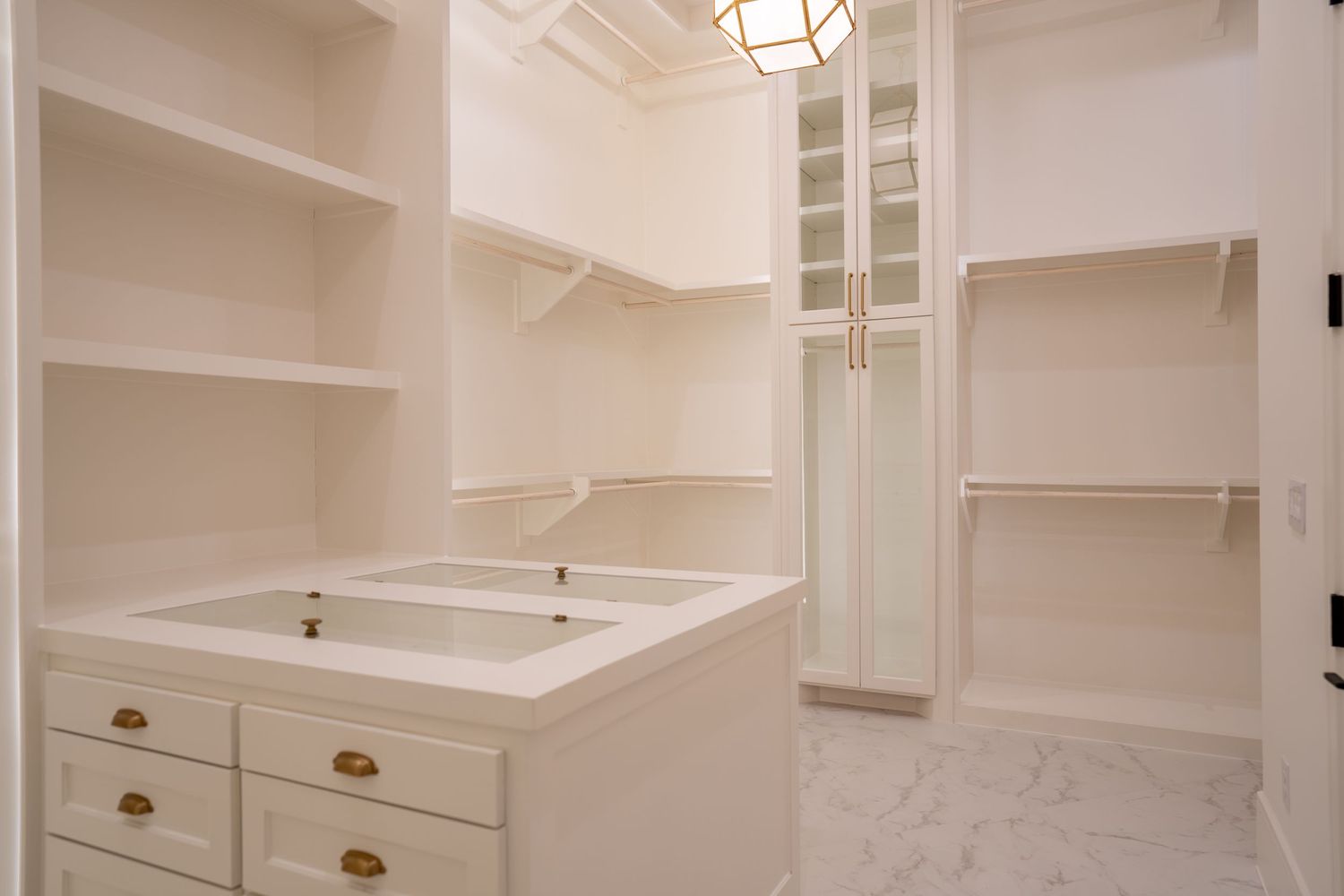 White built-in closet system with drawers, shelving, and marble countertops.