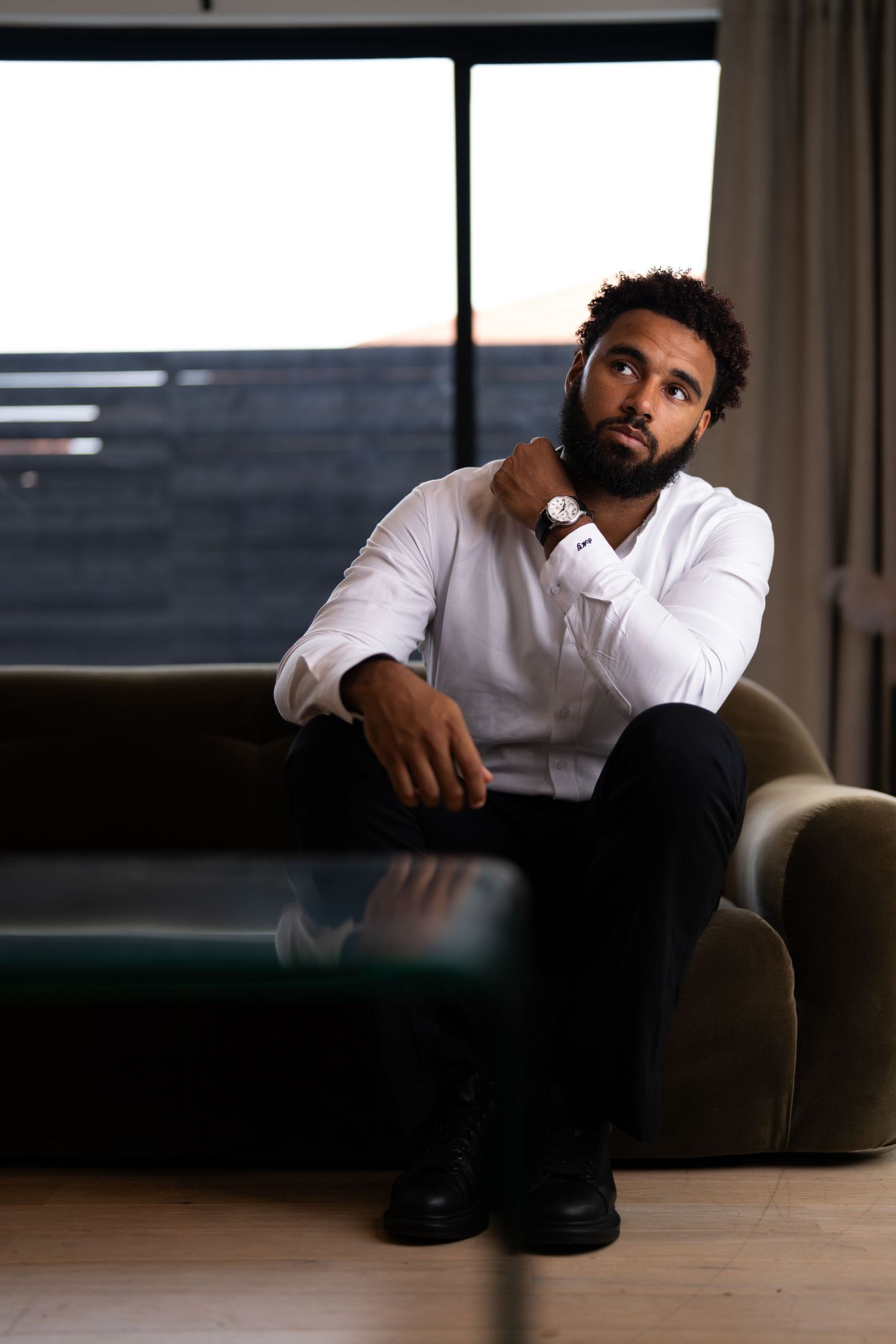 DFW Professional indoor portrait of man in white shirt sitting thoughtfully in modern room. DFW young and rich.