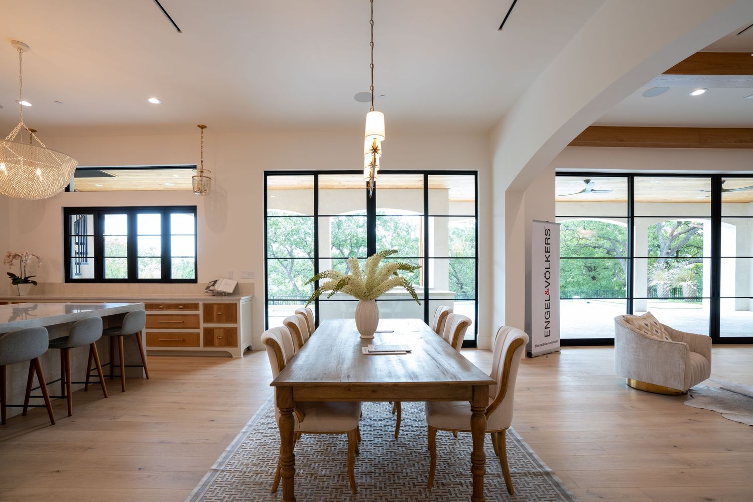 Open concept dining and living space with large windows and modern pendant lighting.