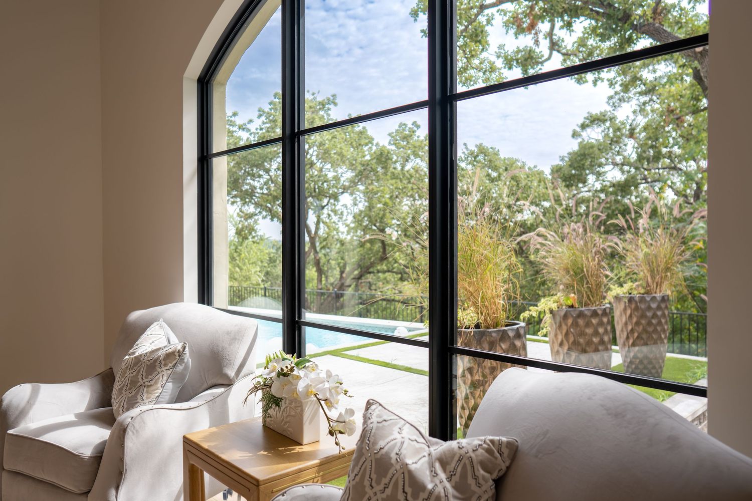 Cozy window nook with plush seating and large arched windows overlooking garden views.